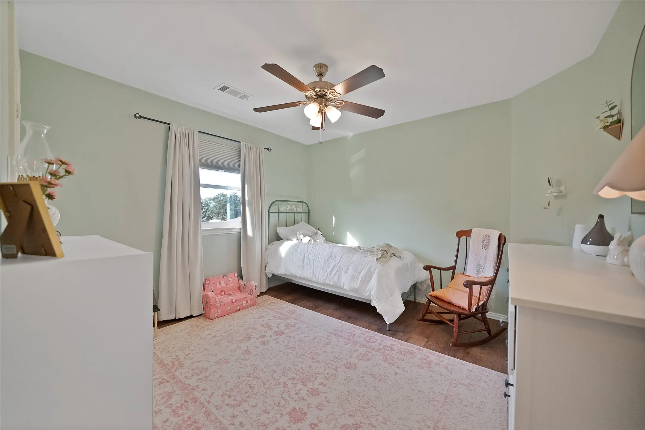 Spacious room featuring wood-finish flooring, a window with natural light, a ceiling fan with integrated lighting, and light-toned wall finishes