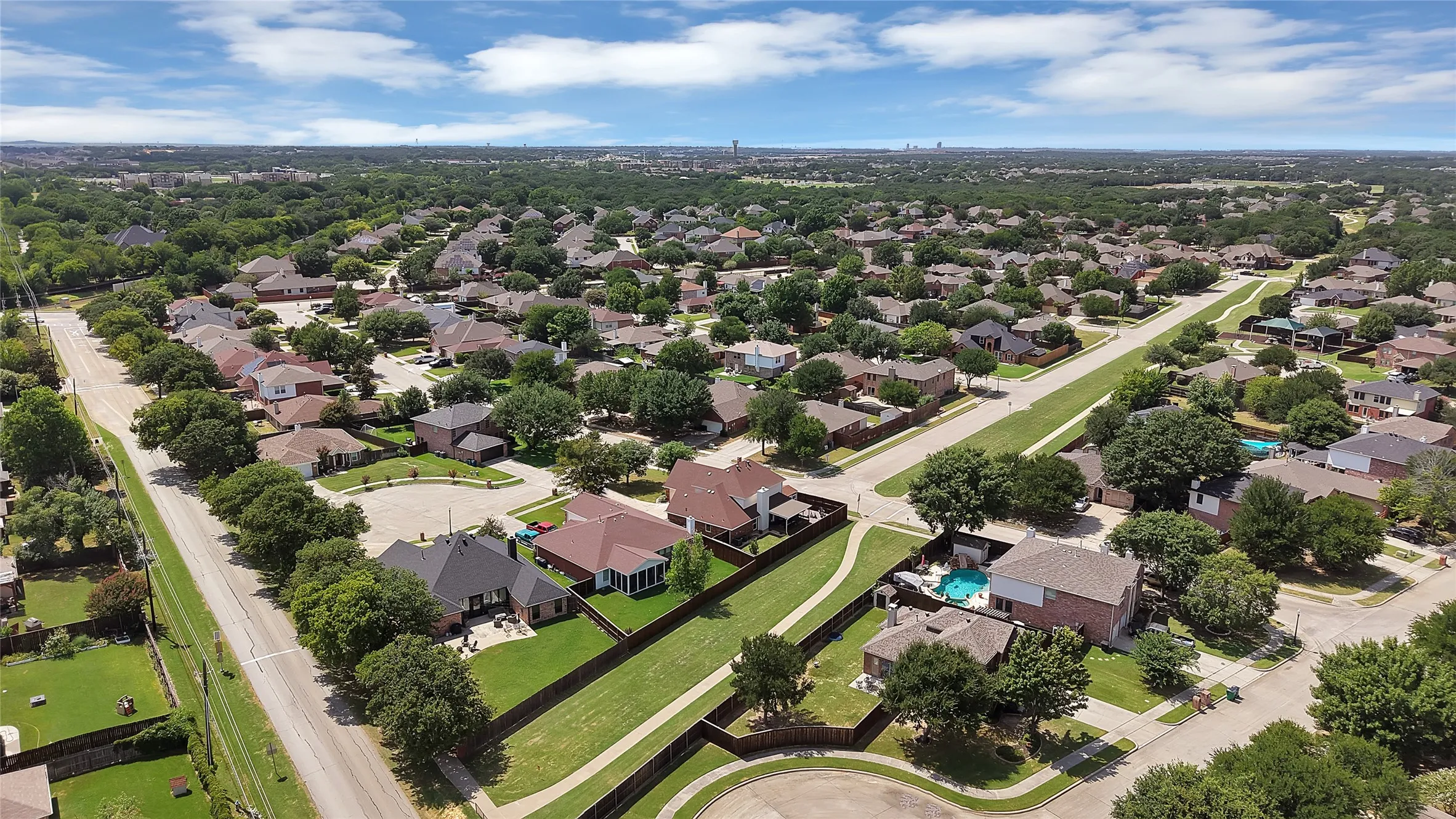 Expansive aerial perspective showcasing a residential area with numerous single-family homes, mature tree canopies, and established street infrastructure
