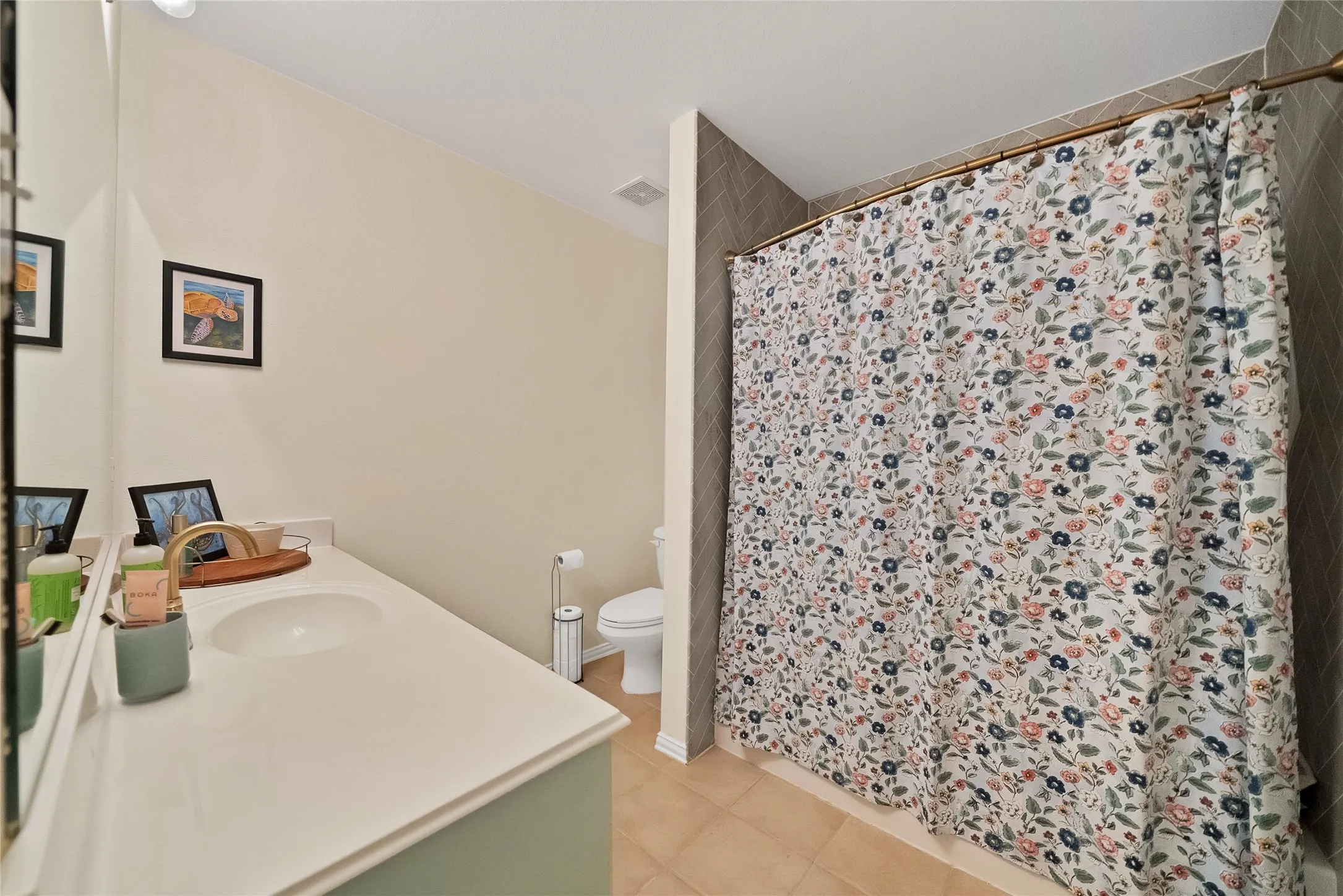 Bathroom featuring a single vanity with an integrated sink, polished brass-finish faucet, and a large wall-mounted mirror