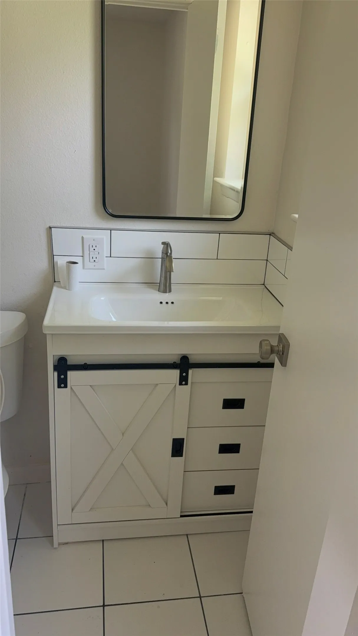 Bathroom vanity featuring a white sink basin, single-handle faucet, and white subway tile backsplash