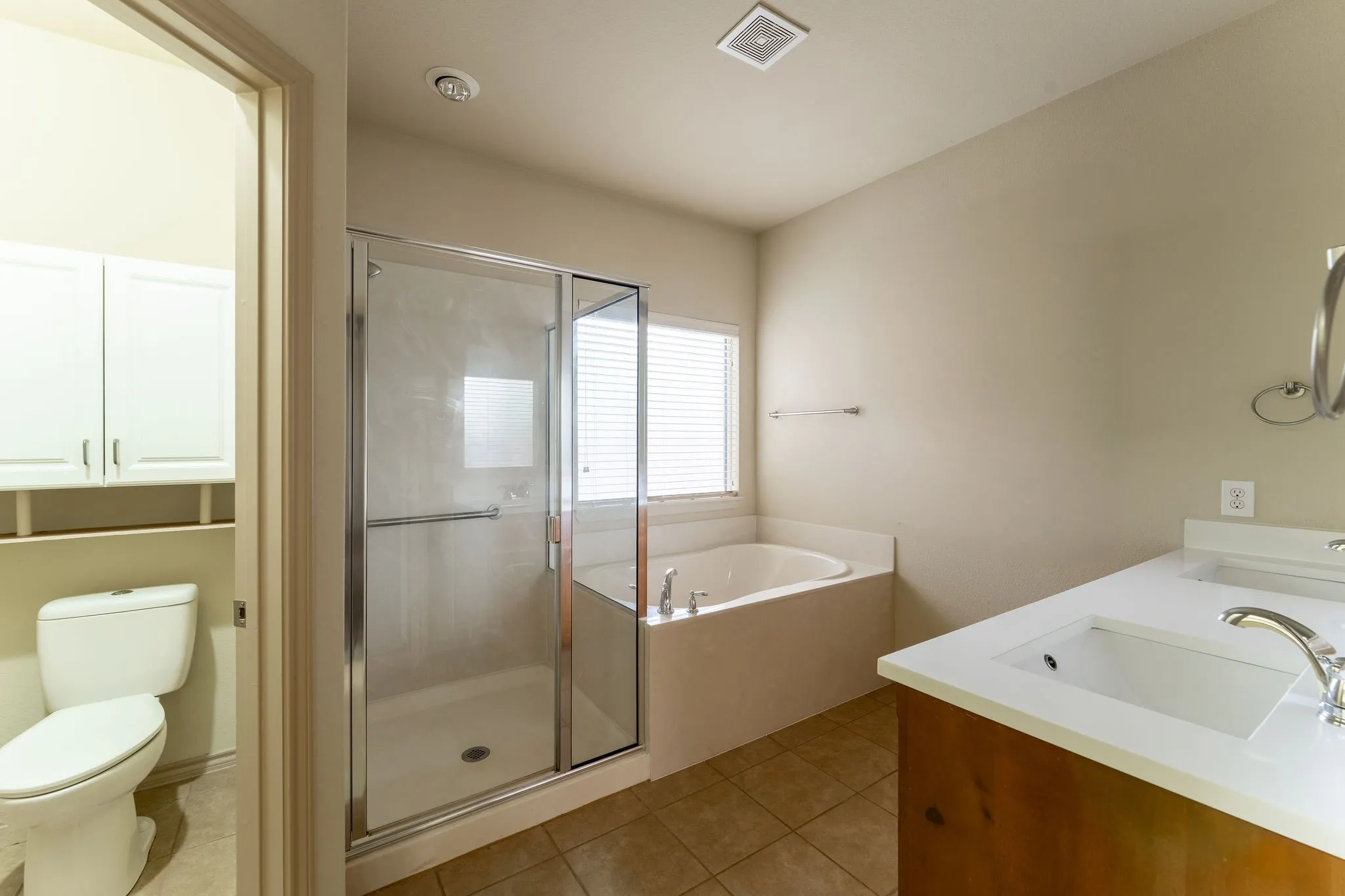 Carpeted interior space with a ceiling fan, a window with horizontal blinds, and an arched doorway leading to a bathroom with tile flooring