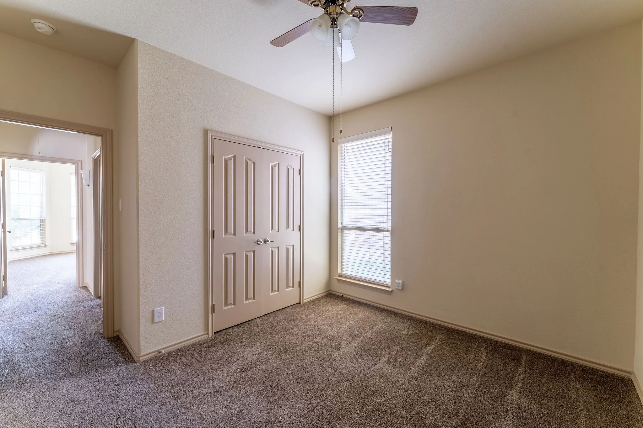 Neutral wall tones with a ceiling fan, carpeted flooring, and a window with blinds