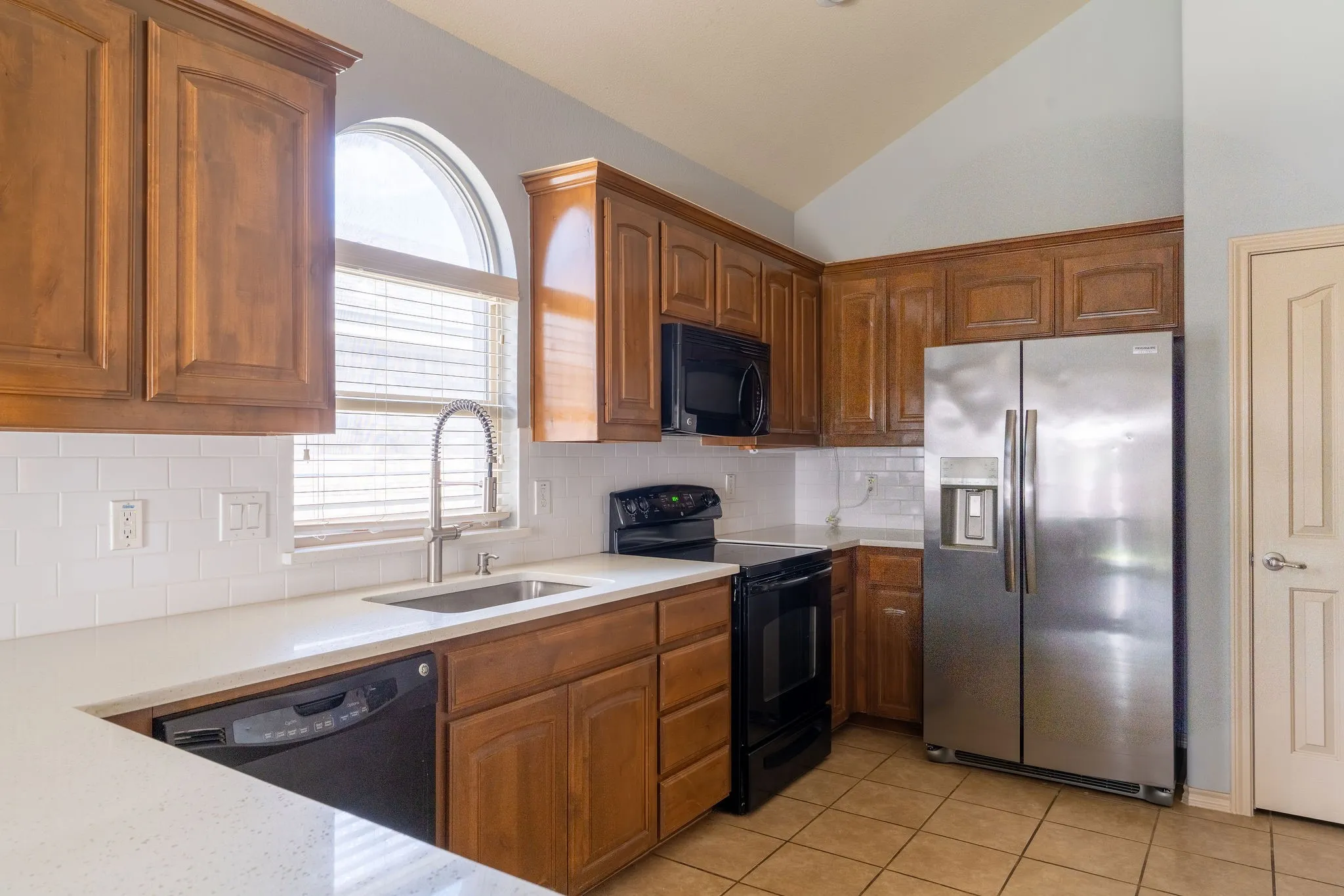 Kitchen featuring wood cabinetry, white countertops, tile backsplash, and stainless-steel refrigerator