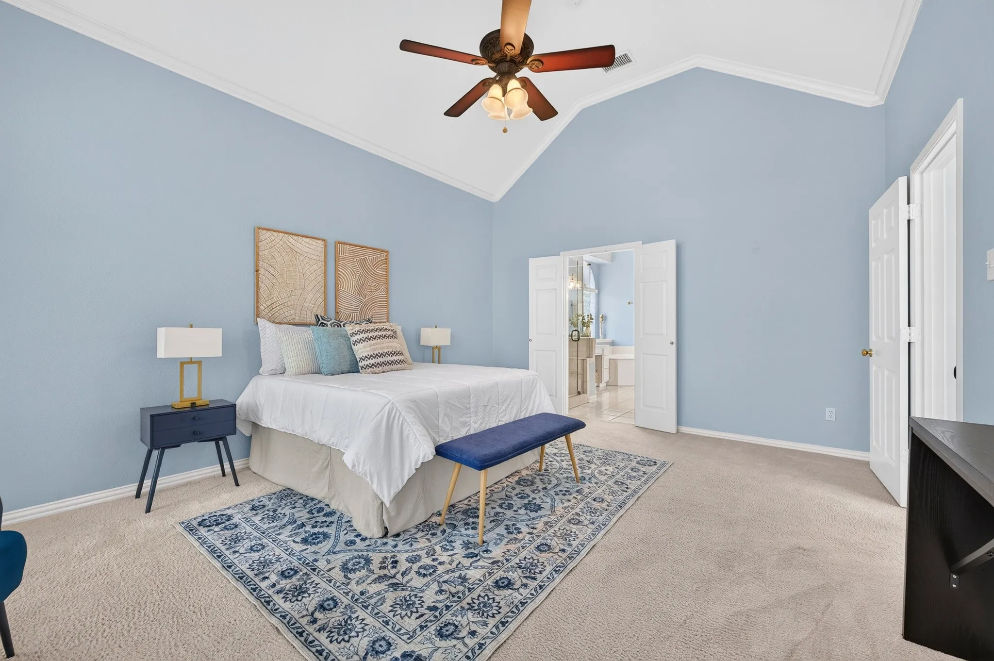 Spacious room featuring a vaulted ceiling with crown molding, ceiling fan, and carpeted flooring