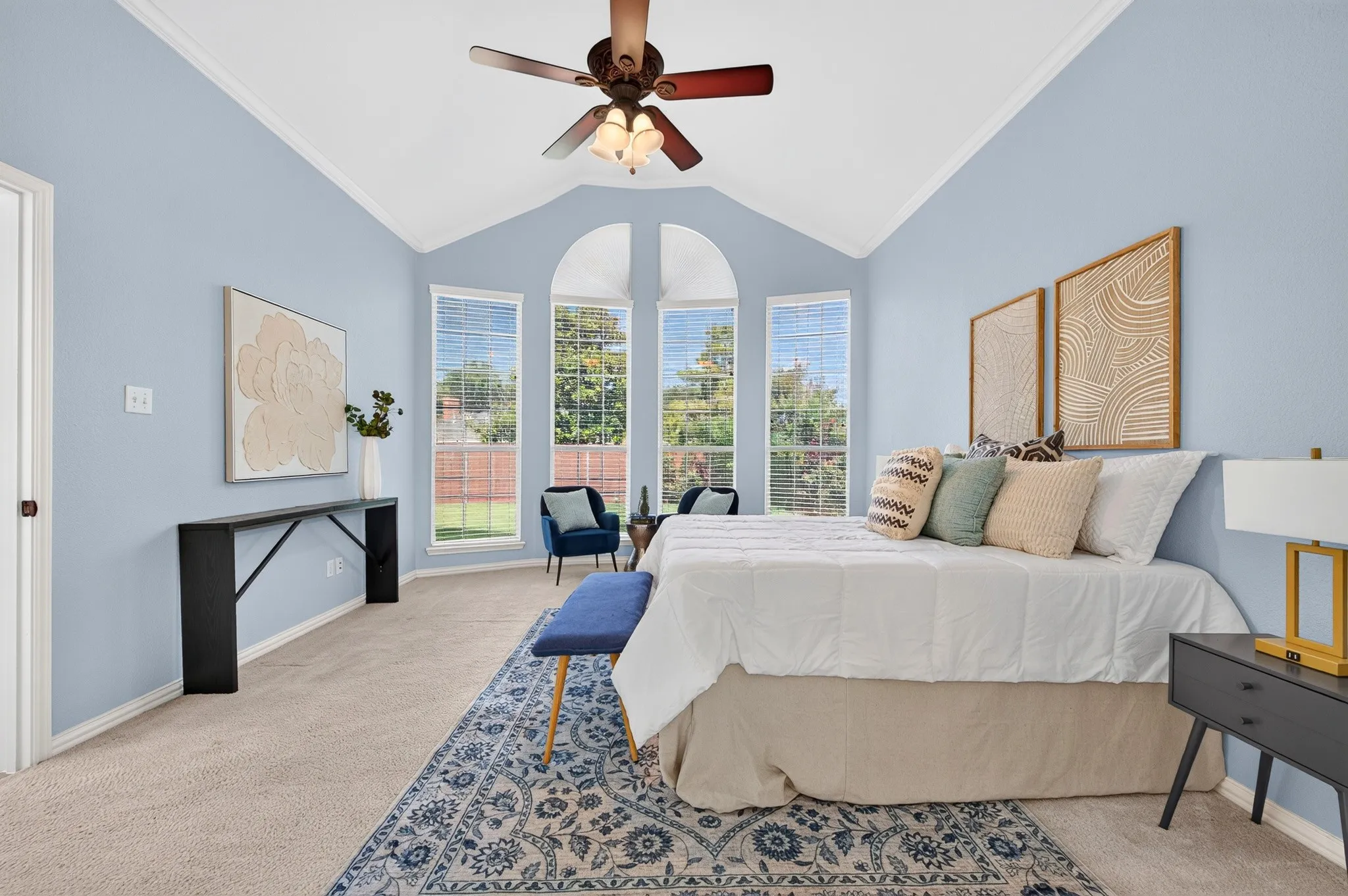 Vaulted ceiling featuring a ceiling fan, three arched windows with blinds, and light blue walls