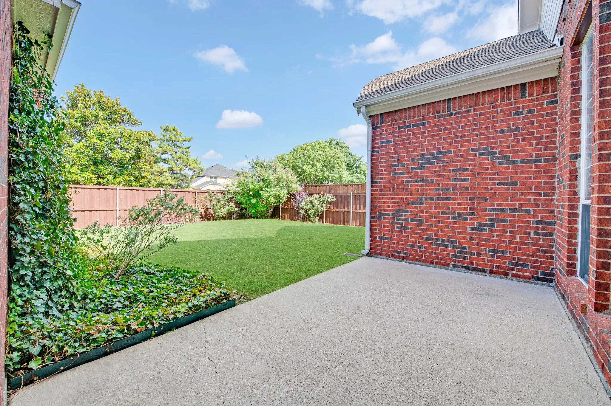 Expansive backyard featuring a manicured lawn, a large concrete patio, and a privacy fence