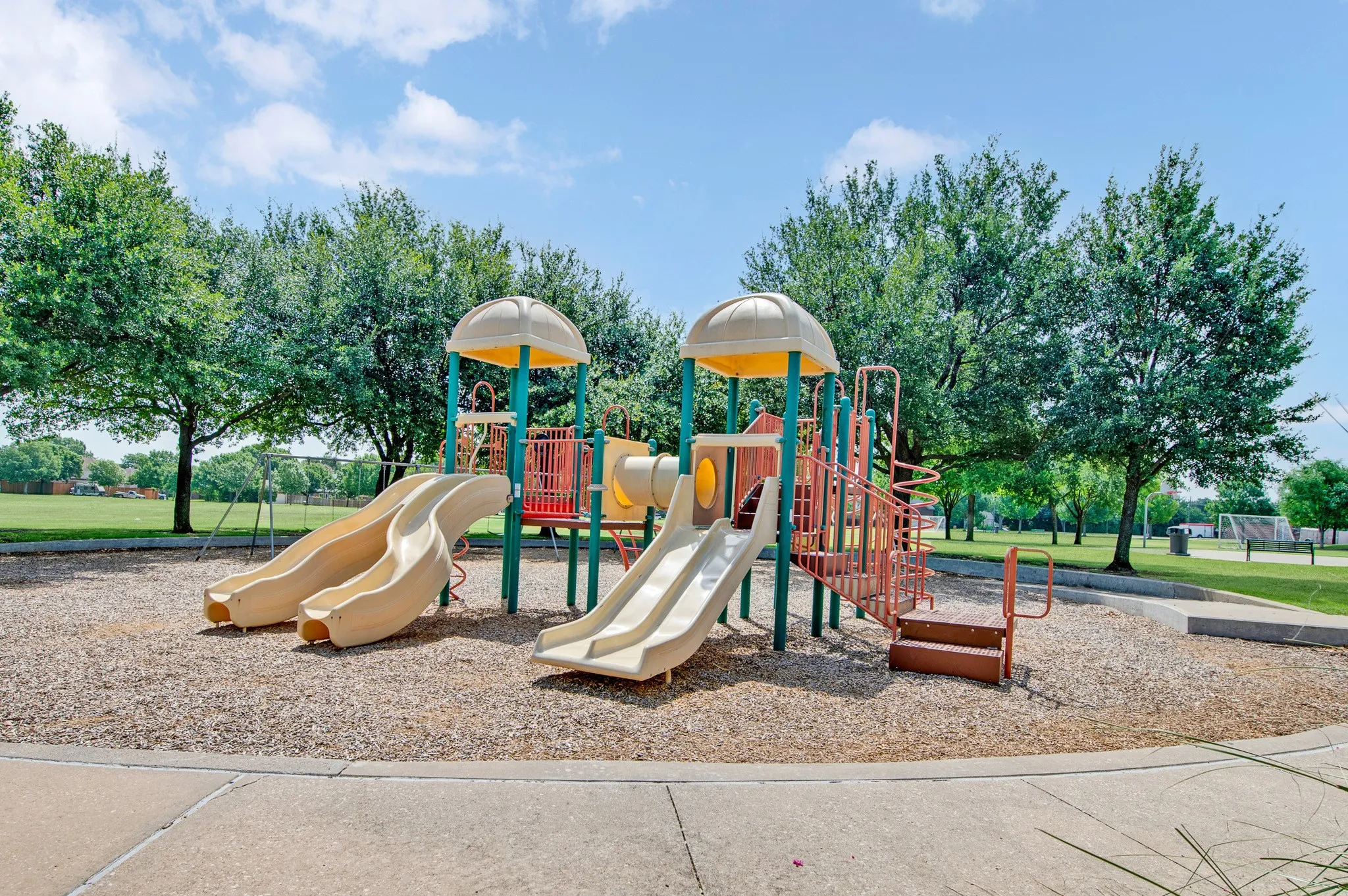 Outdoor recreational area featuring a multi-level play structure with slides and climbing elements