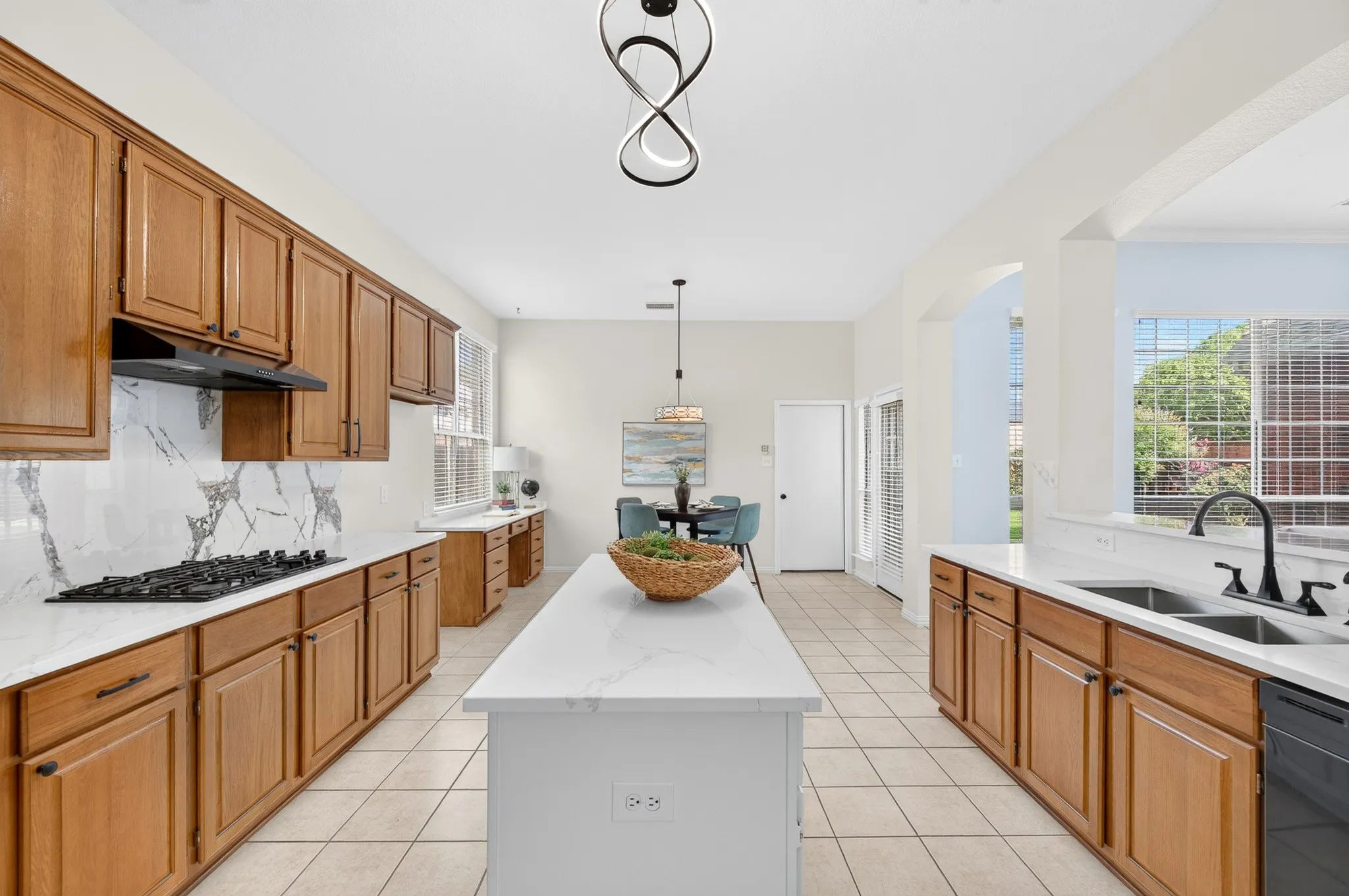 Spacious kitchen featuring light wood cabinetry, quartz countertops, a stone slab backsplash, a central island, and tile flooring