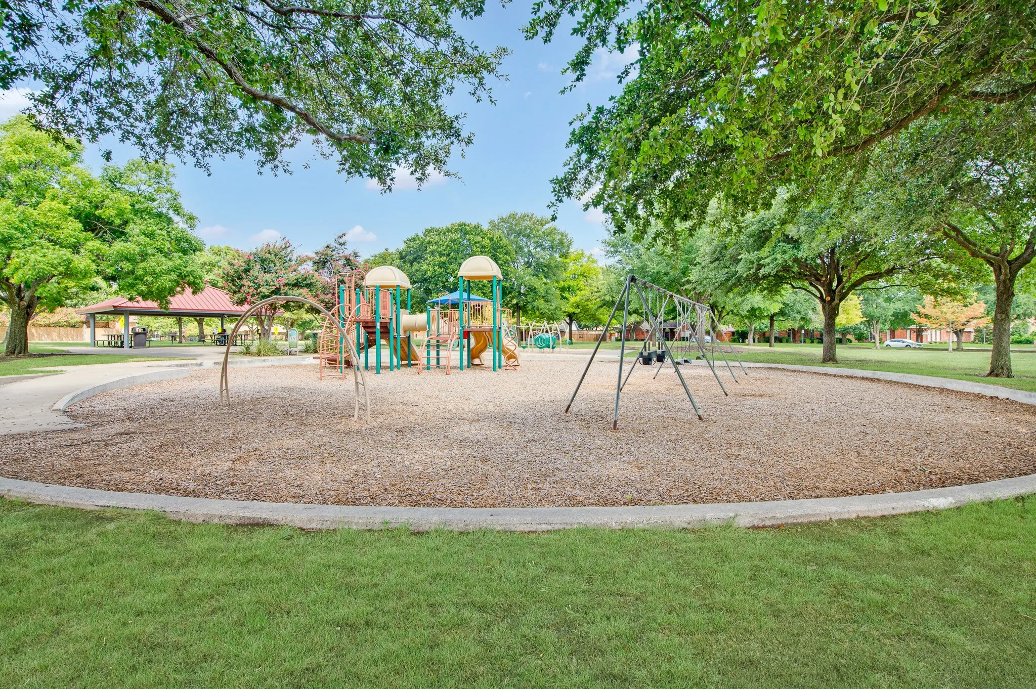 Outdoor play area featuring multiple structures, swings, and wood chip surfacing