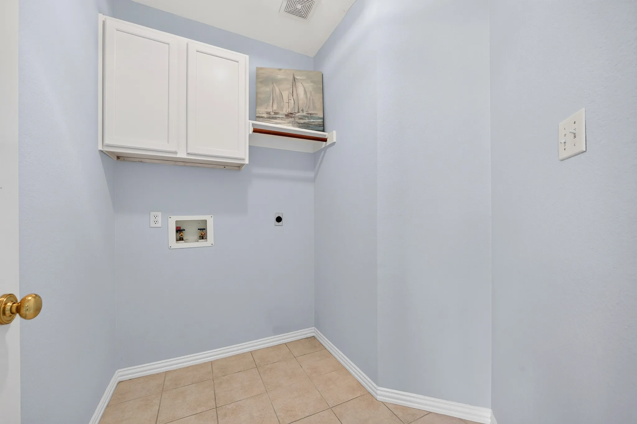 Dedicated utility space featuring tile flooring and light blue walls