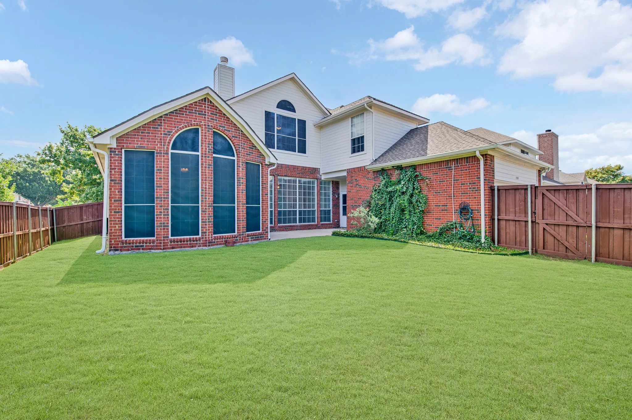Expansive green lawn with a two-story brick and siding exterior