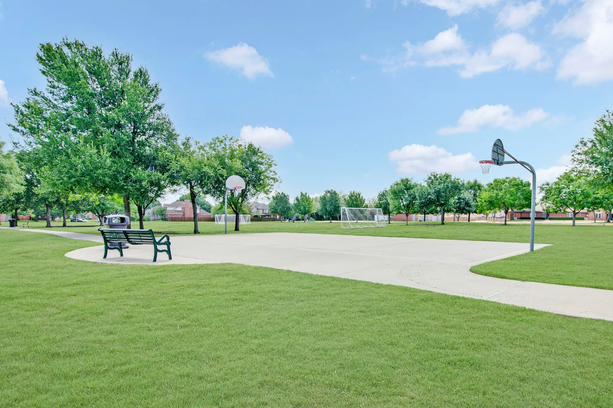 Community park featuring a concrete basketball court, a soccer goal, and a paved walking path