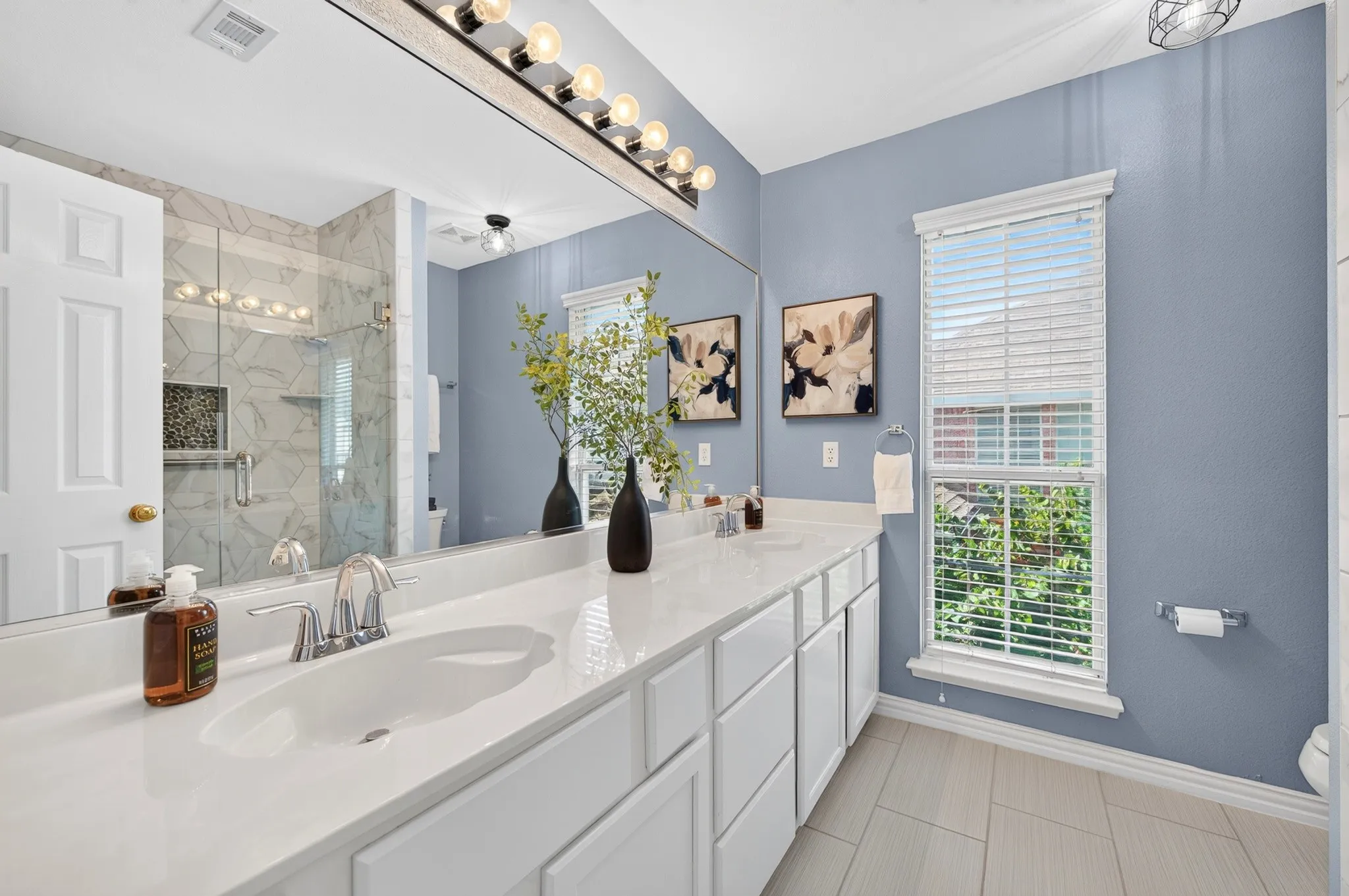 Spacious vanity with dual undermount sinks, chrome fixtures, and white cabinetry