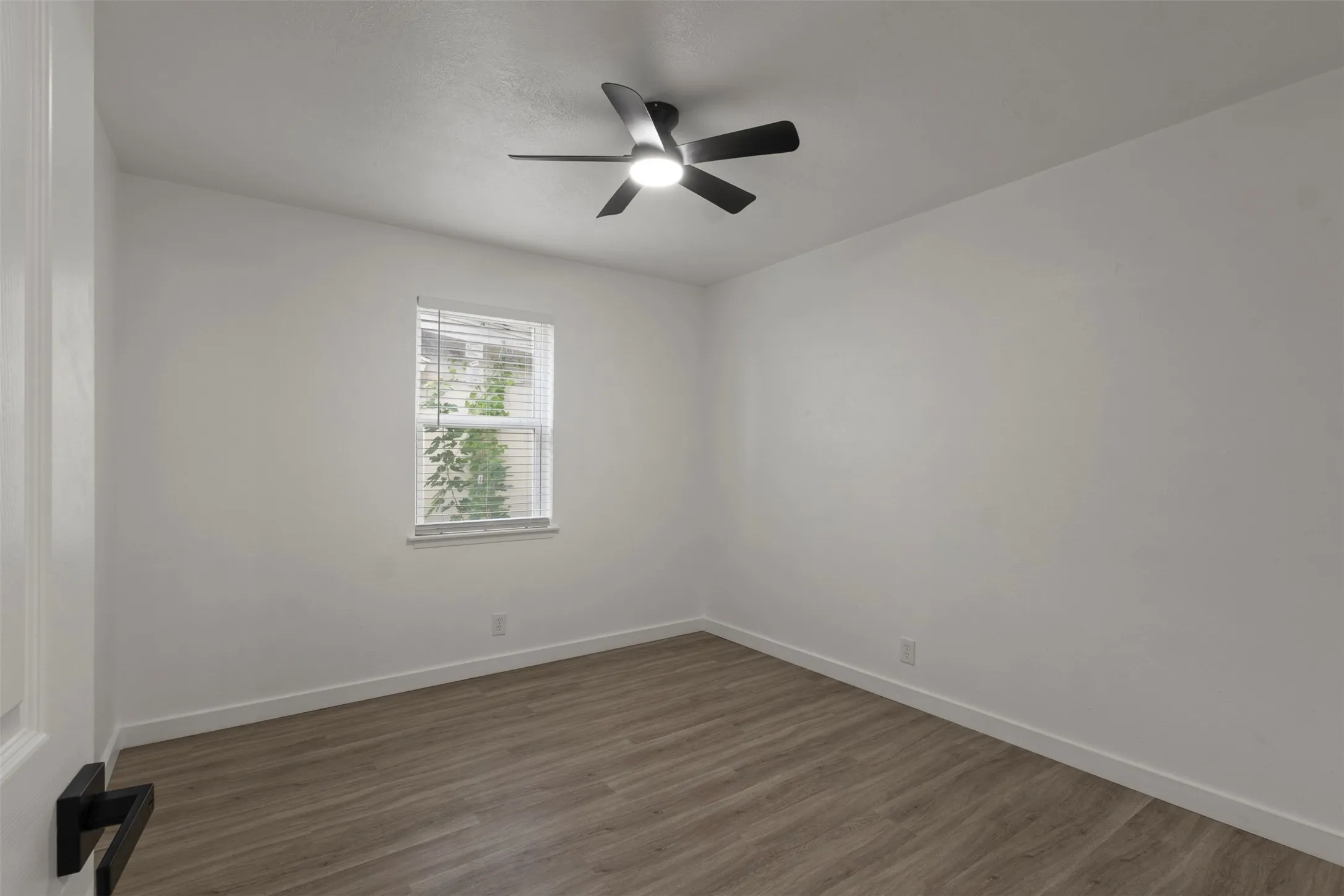 Third bedroom featuring luxury vinyl flooring , white walls, and a modern ceiling fan with integrated lighting and a closet.