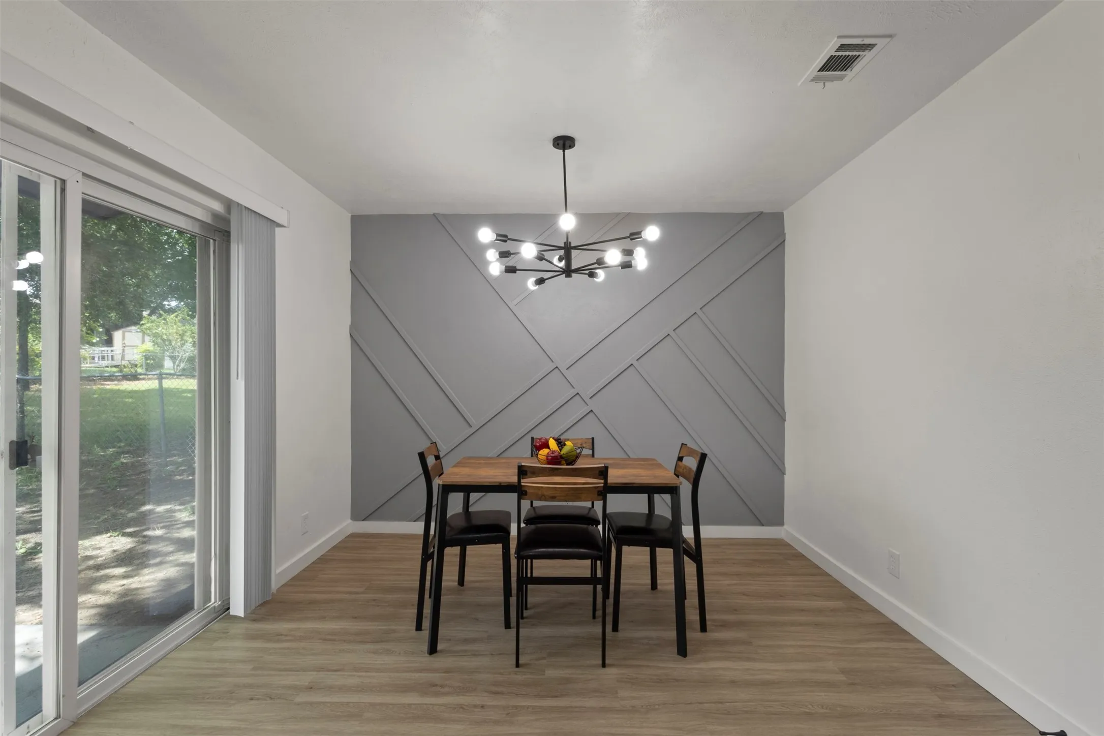 dining area with glass sliding door for natural lighting and an accent wall