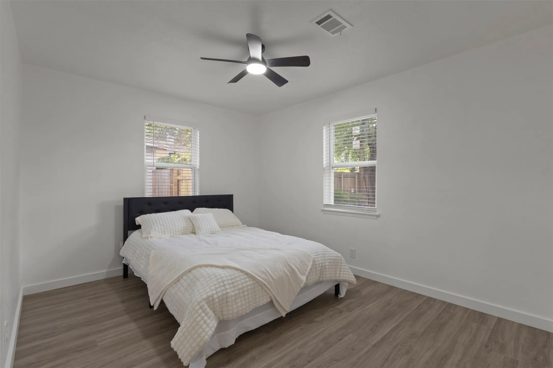 Primary bedroom with luxury vinyl floor windows for natural lighting and a celling fan