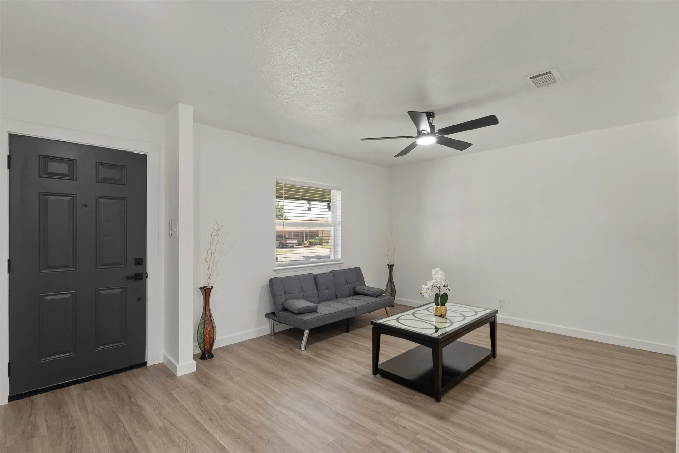 Living room with luxury vinyl flooring, a celling fan and window for natural lighting
