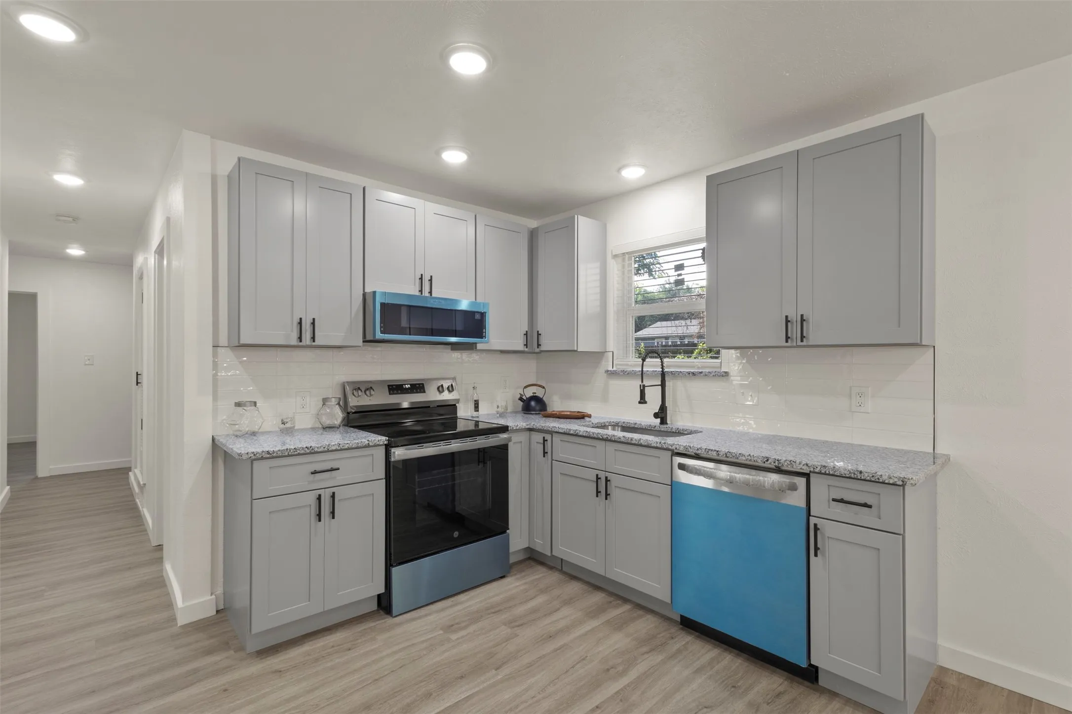 Open kitchen with new cabinets and stainless steel appliances and tons of lighting