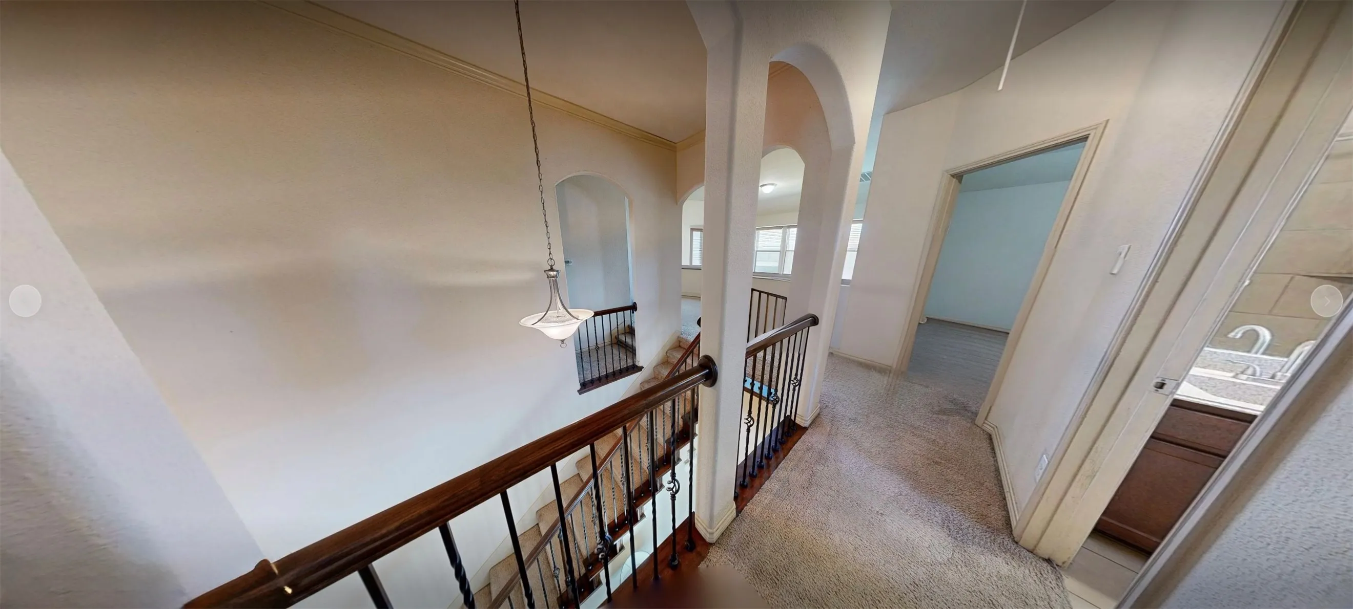 Second Floor hallway with arched wall openings and an open staircase featuring a wood handrail with metal balusters