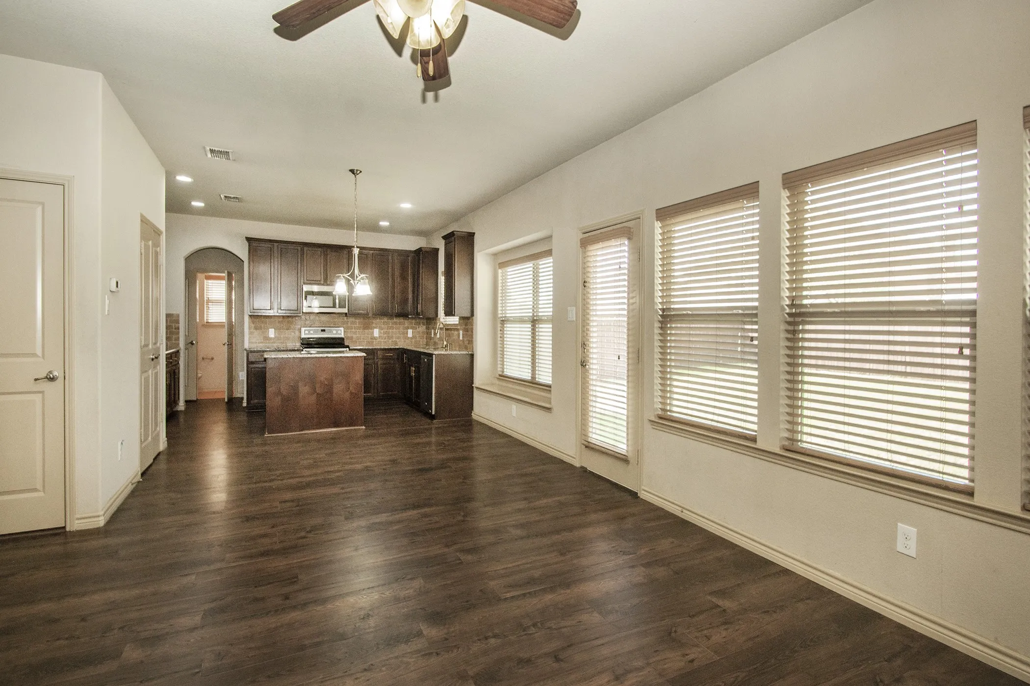Open-concept living space with dark wood-finish flooring, recessed lighting, and a ceiling fan