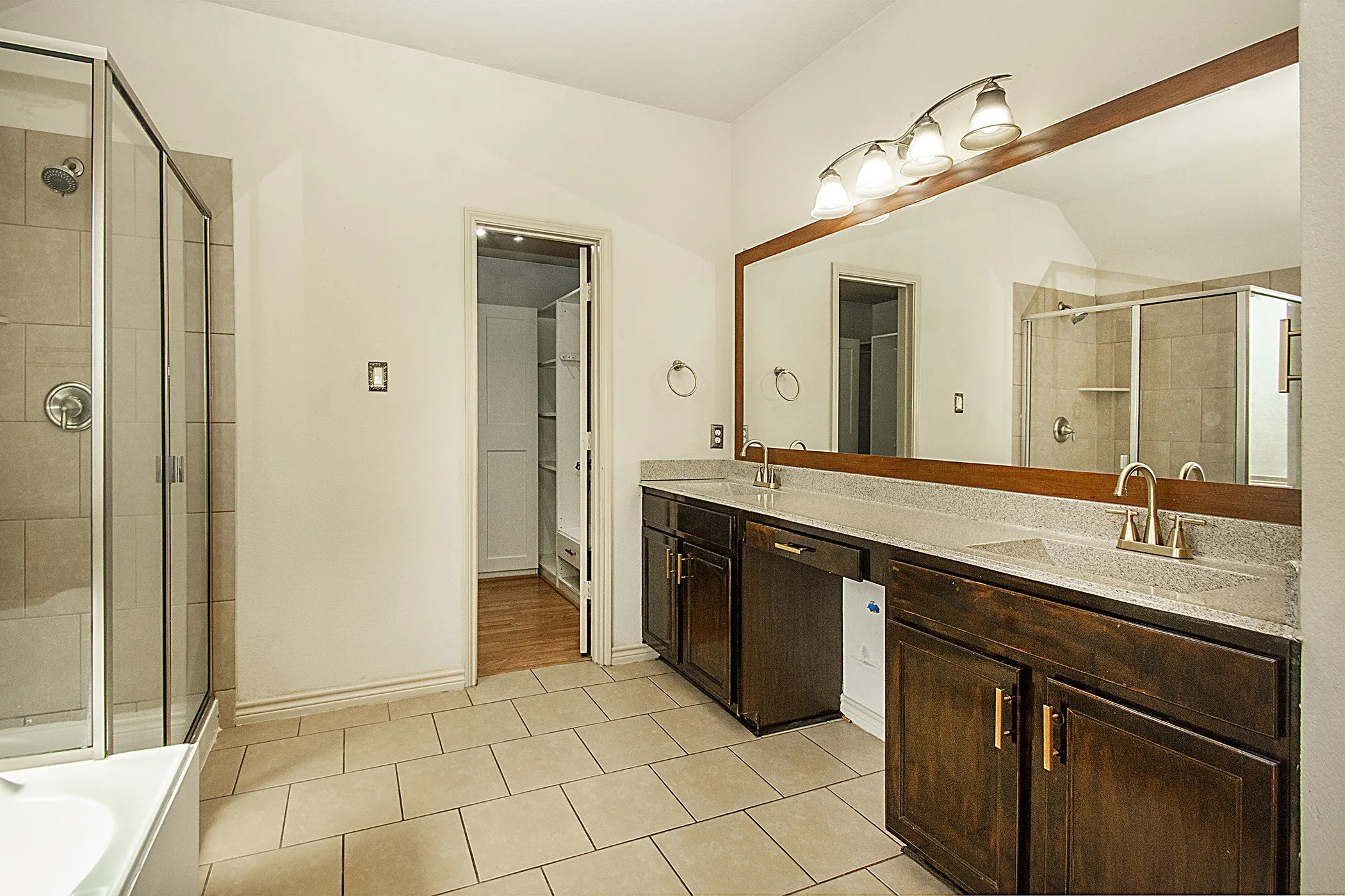 Double vanity with undermount sinks, tile flooring, glass-enclosed shower, and built-in cabinetry
