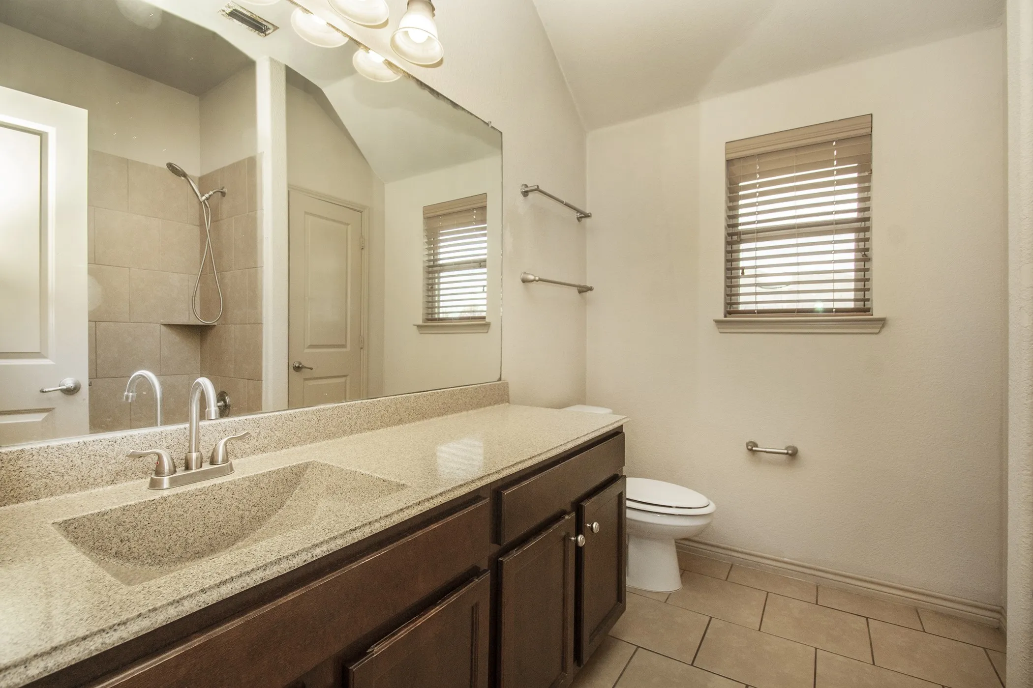 Vanity with integrated sink, dark wood-finish cabinetry, and a light-colored countertop