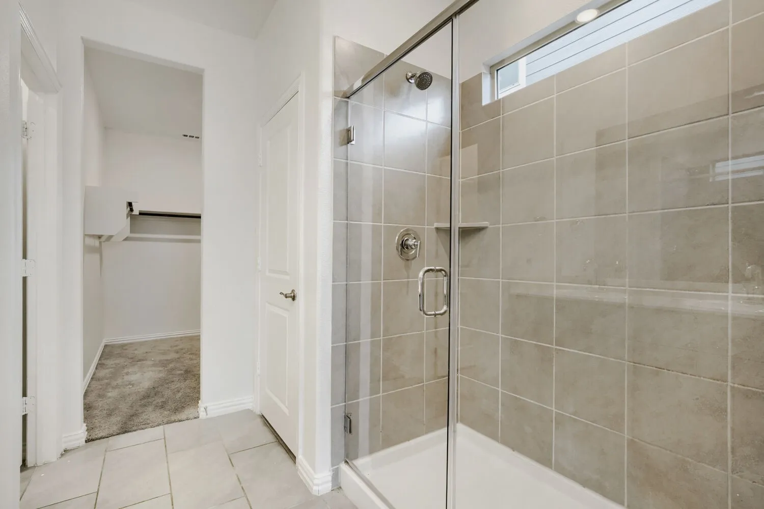 Glass-enclosed shower with tile surround and integrated shelving