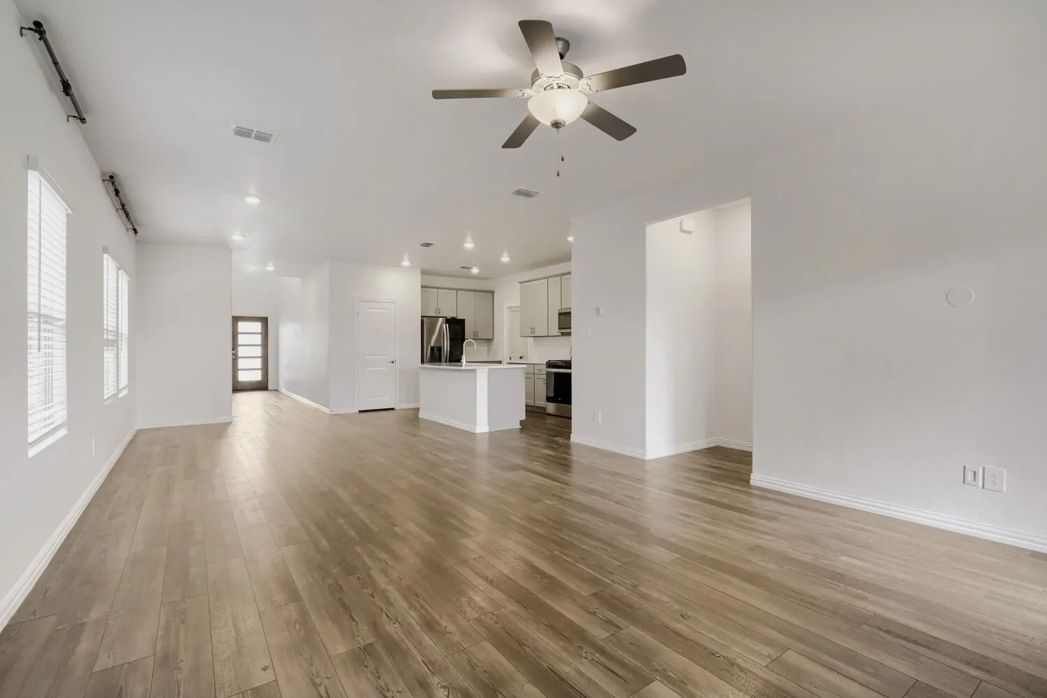 Expansive living area featuring wood-finish flooring, recessed lighting, and a ceiling fan