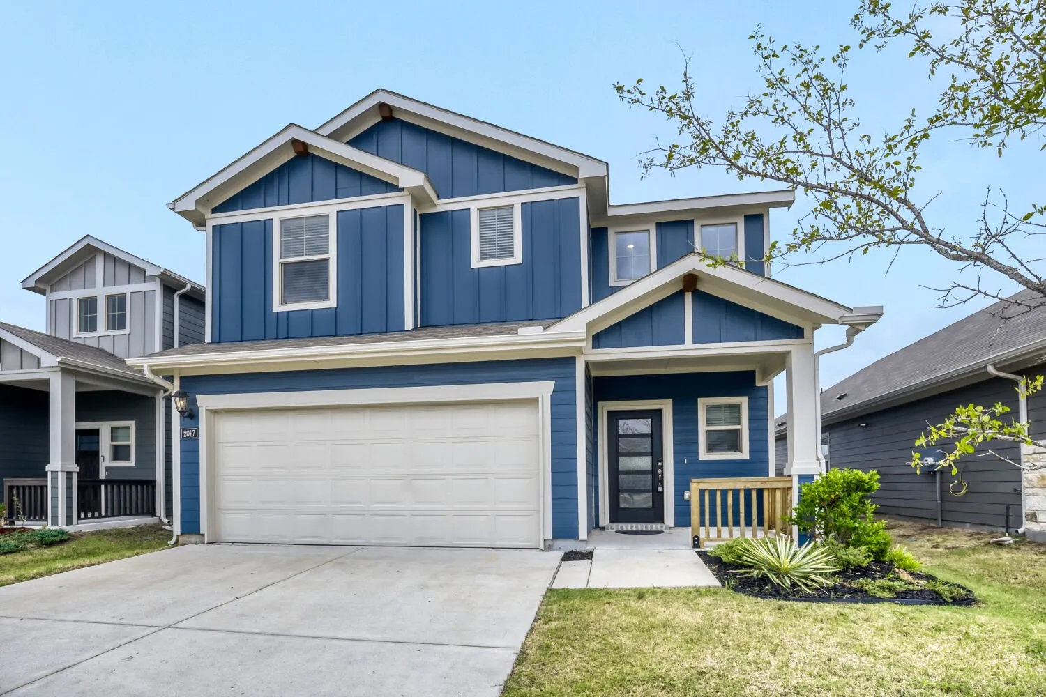 Two-story residence featuring blue vertical panel siding and white trim accents