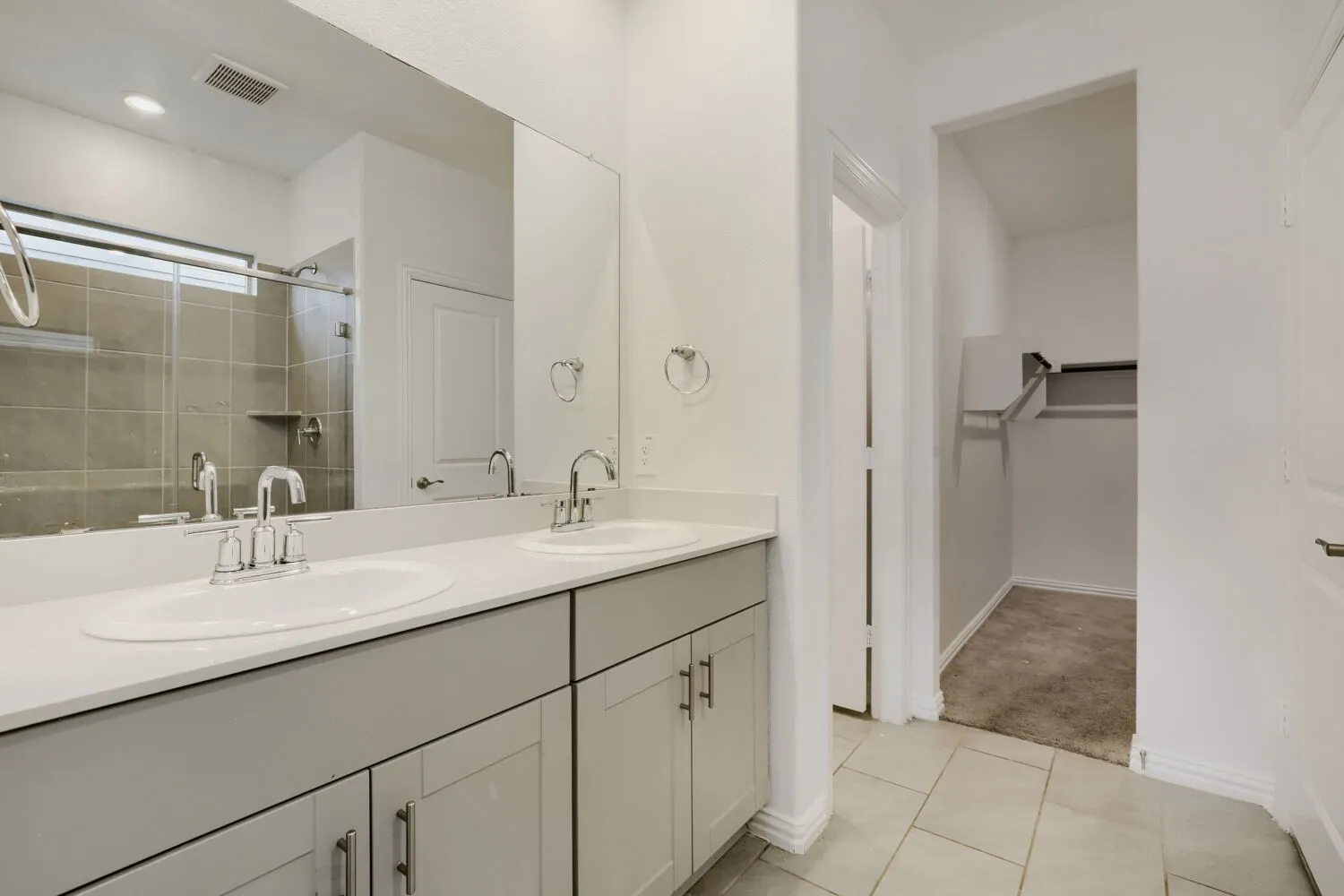 Bathroom featuring a dual vanity with light gray cabinetry and white countertops