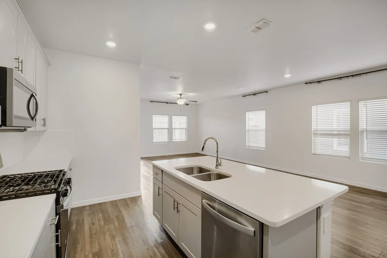 Kitchen island featuring a dual basin sink, stainless steel faucet, and dishwasher