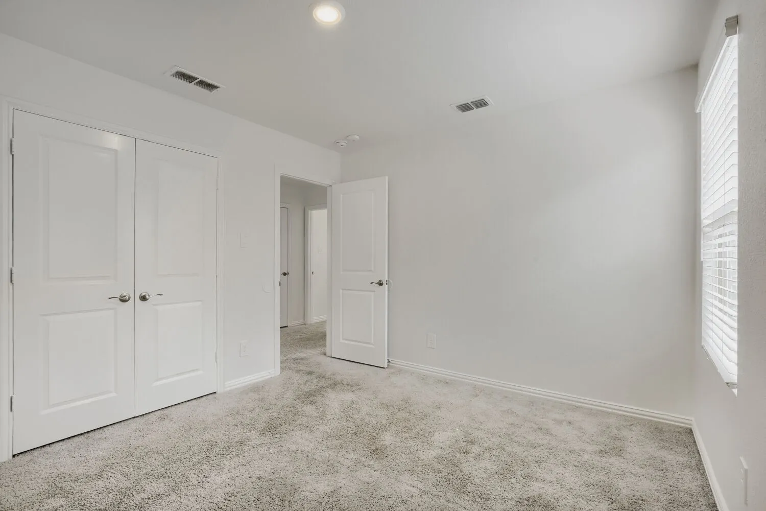 Carpeted room featuring a double-door closet, white walls, recessed lighting, and a window with blinds