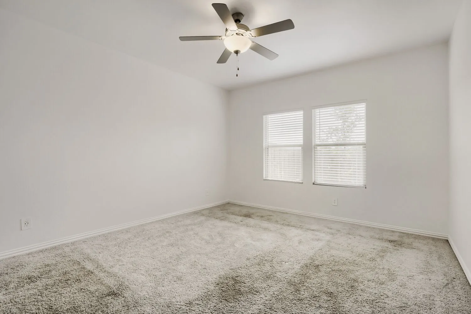 Room featuring light gray carpeting, neutral wall finishes, and a ceiling fan with integrated lighting