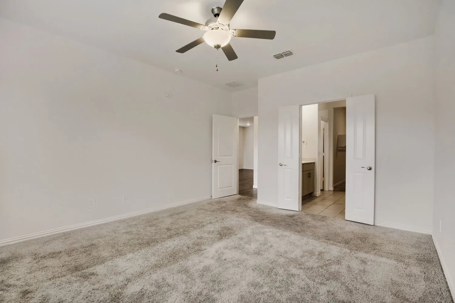 Spacious interior with neutral-toned walls, gray carpet flooring, and a ceiling fan with integrated lighting
