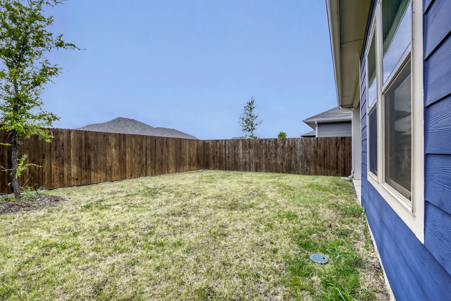 Expansive backyard featuring a full privacy fence and a manicured lawn