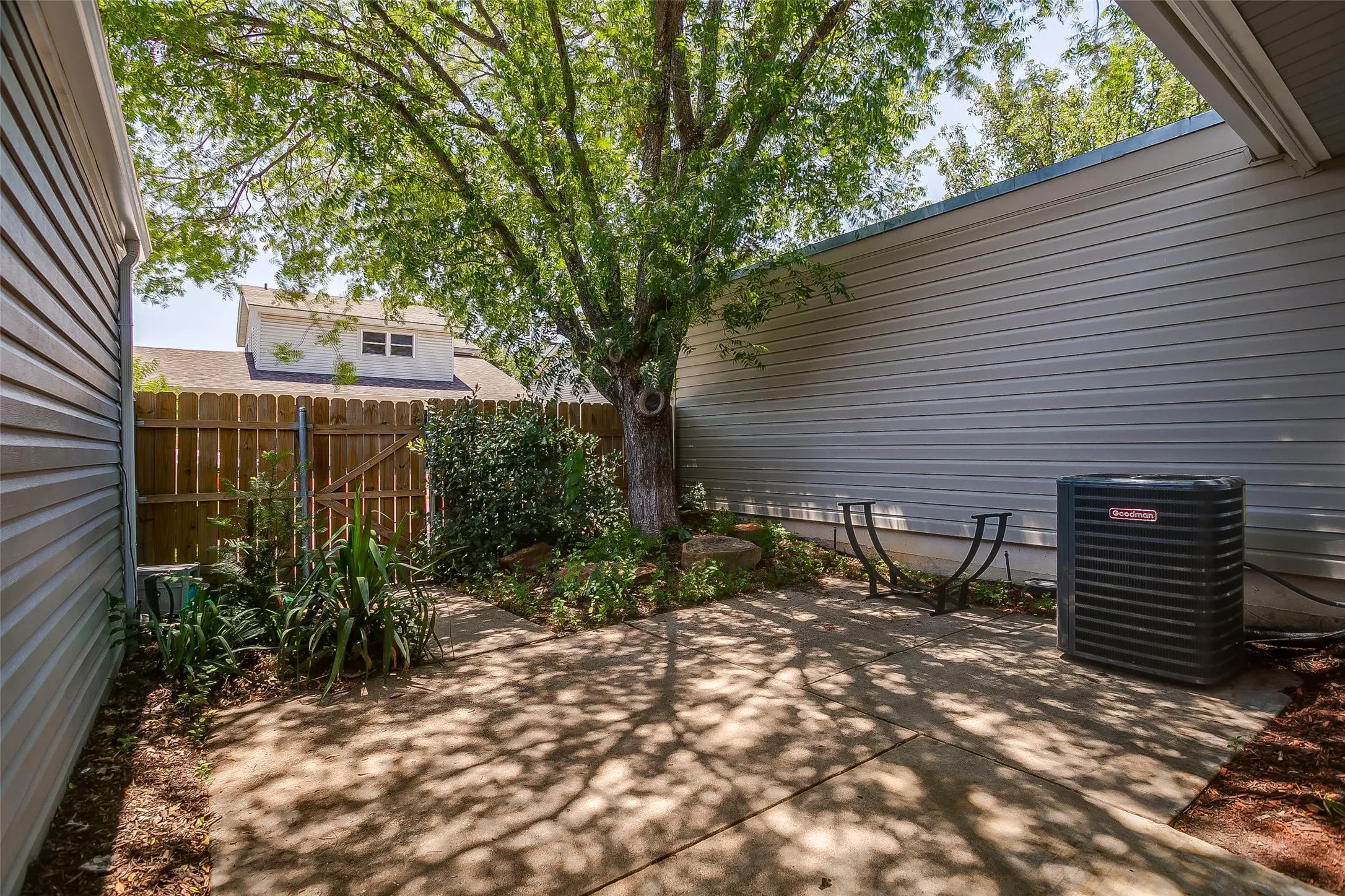 Fenced back patio with mature shade trees for privacy.