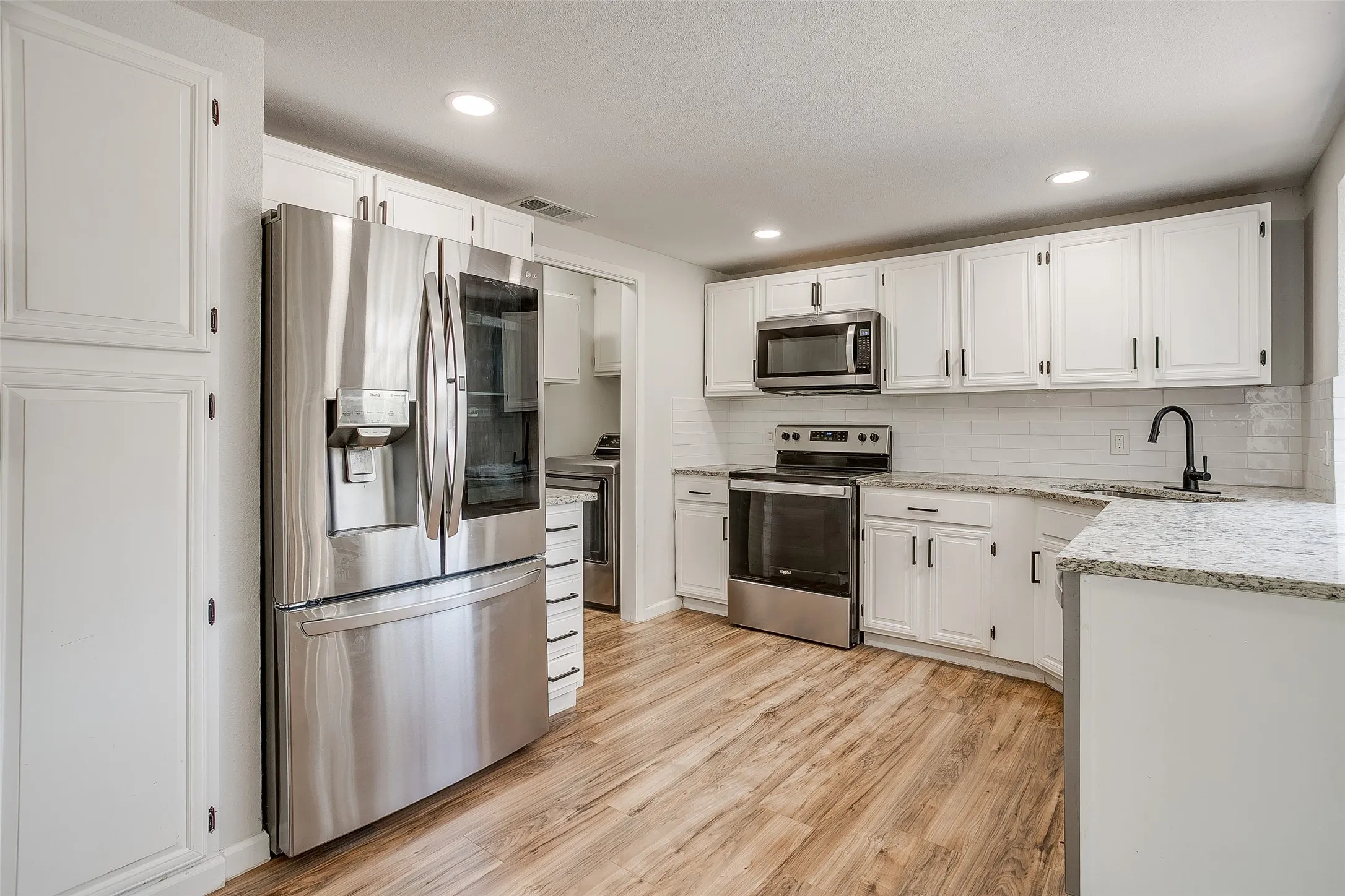 Kitchen featuring stainless steel appliances and white cabinetry.