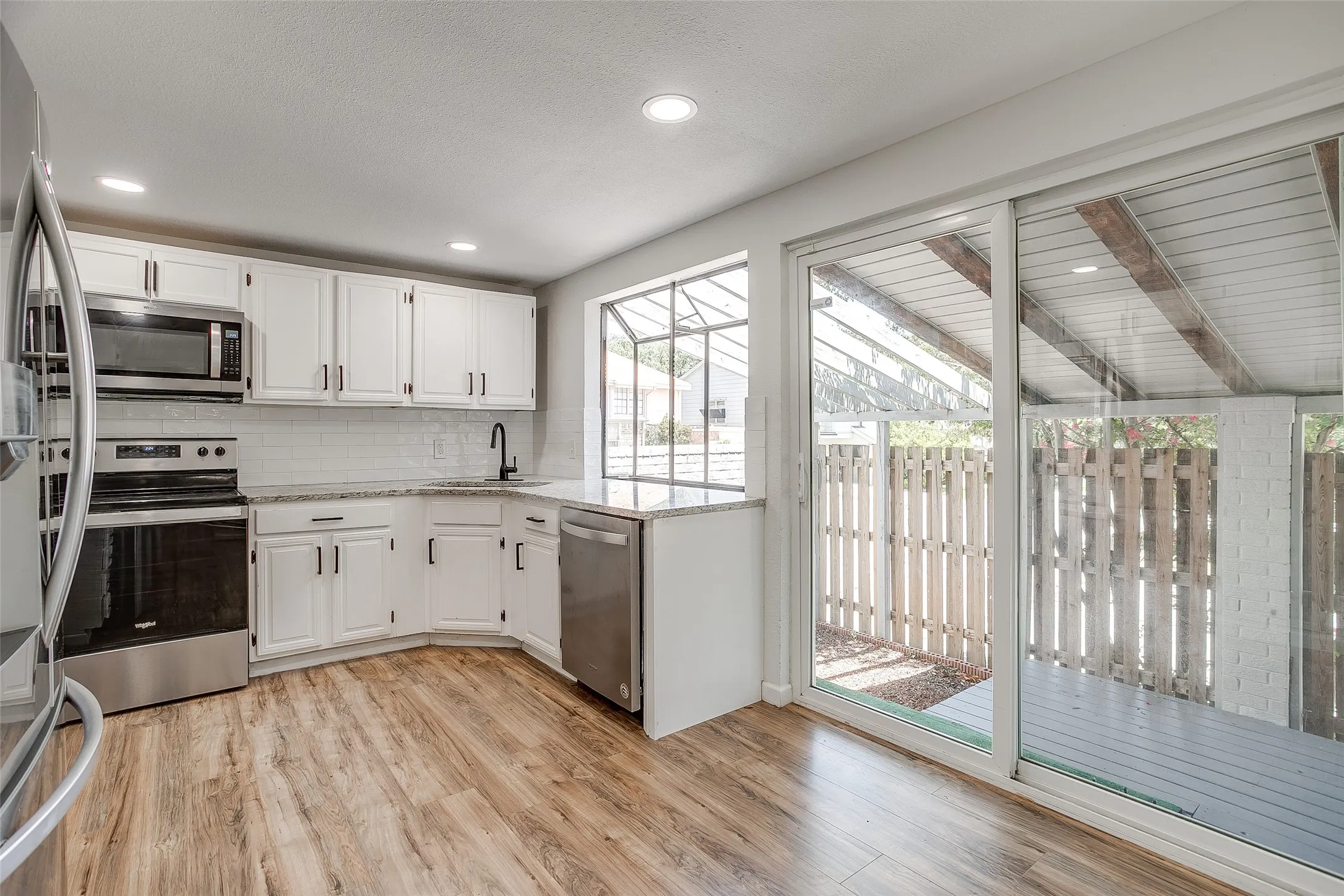 Kitchen with granite counters and stainless steel appliances, with backyard access.