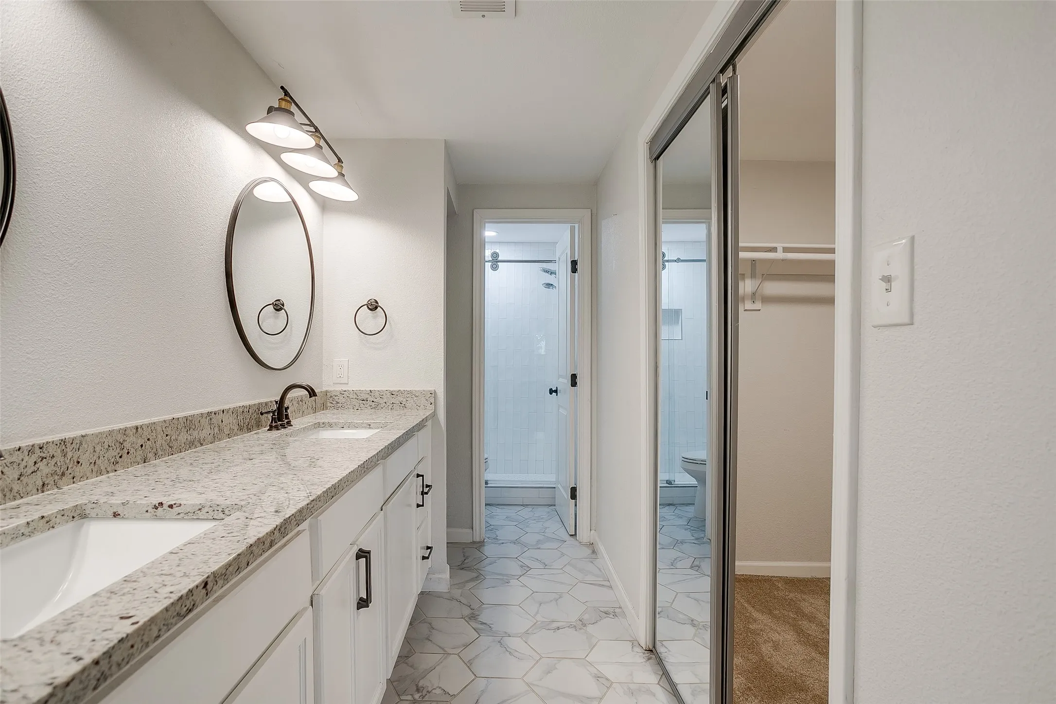 Primary suite bath with double sinks and tile flooring.