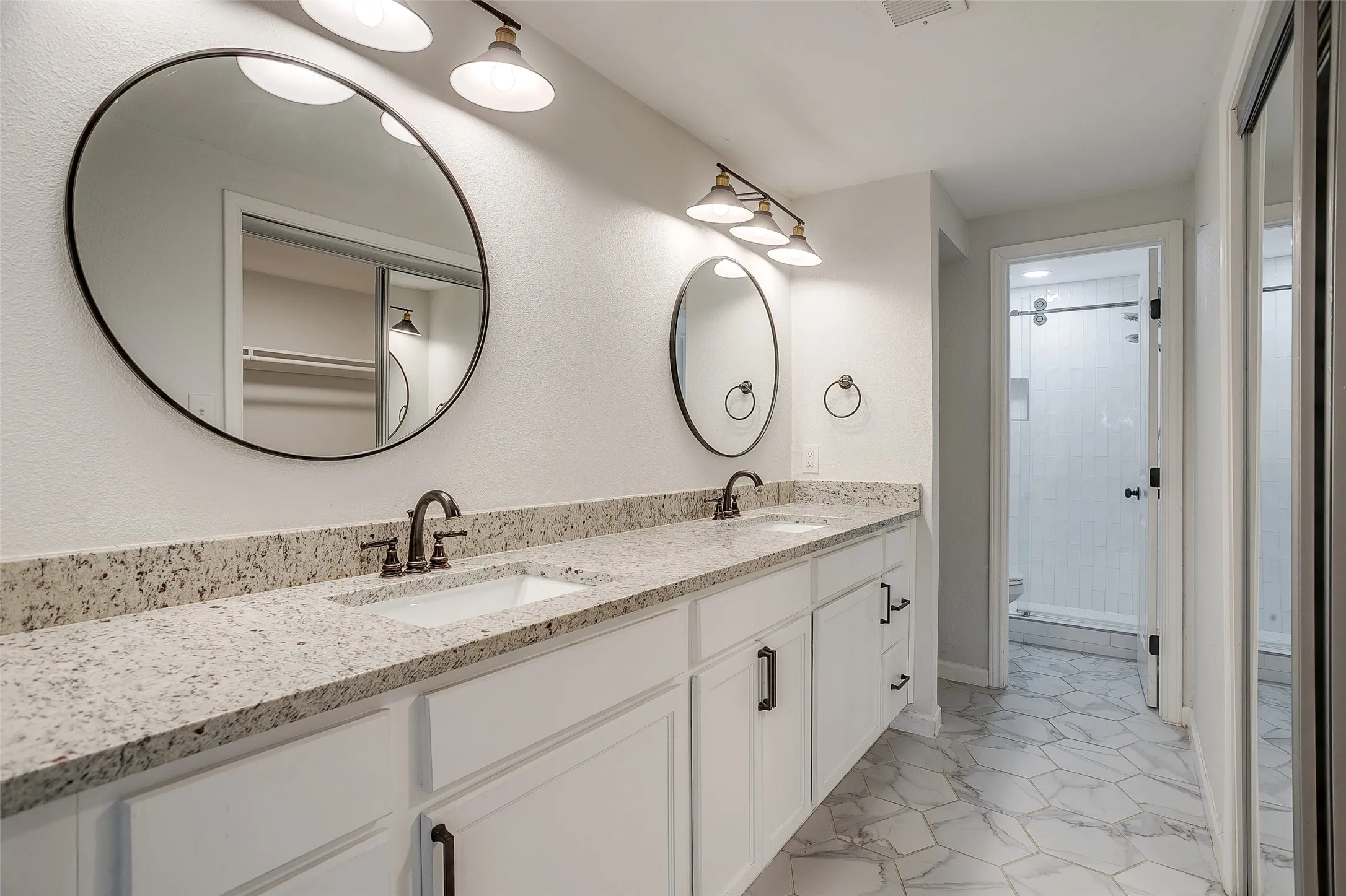 Primary suite bath with double sinks and tile flooring.