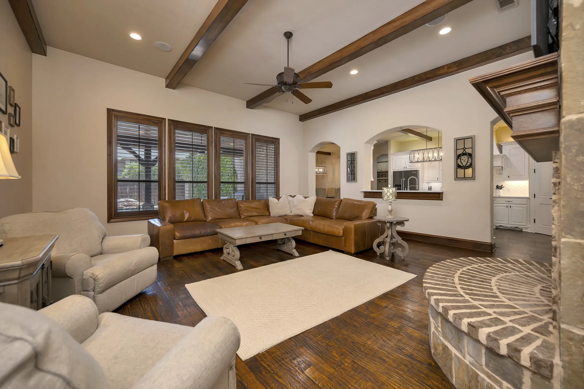 Wood Rich Features on the Wall of Windows, Ceiling Beams and Flooring Accent the Spacious Living Room.  Don't forget about the Plantation Shutters Throughout!
