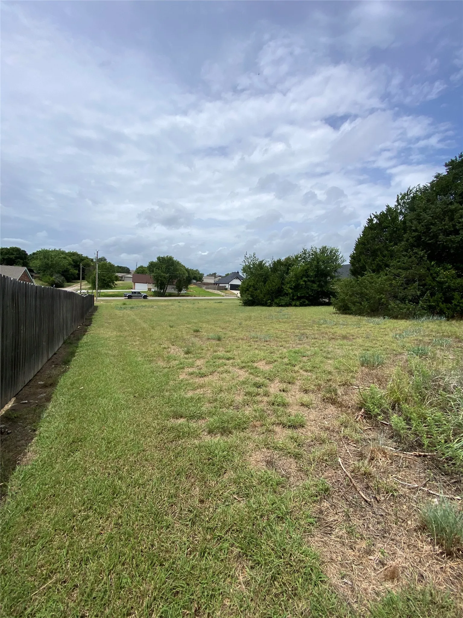 Expansive lot featuring a dark-toned privacy fence and mature perimeter trees