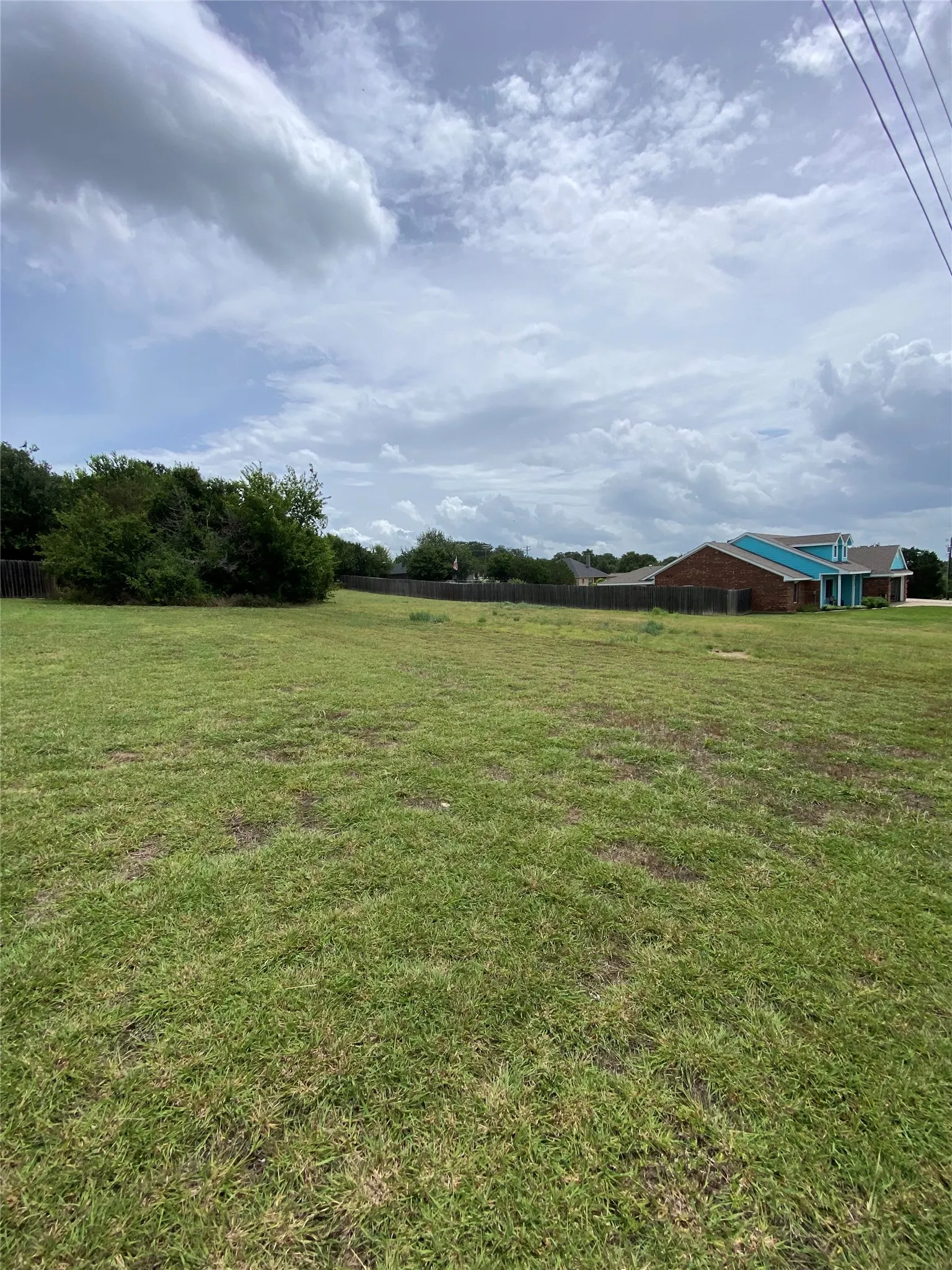Expansive green lot with partially wooded perimeter