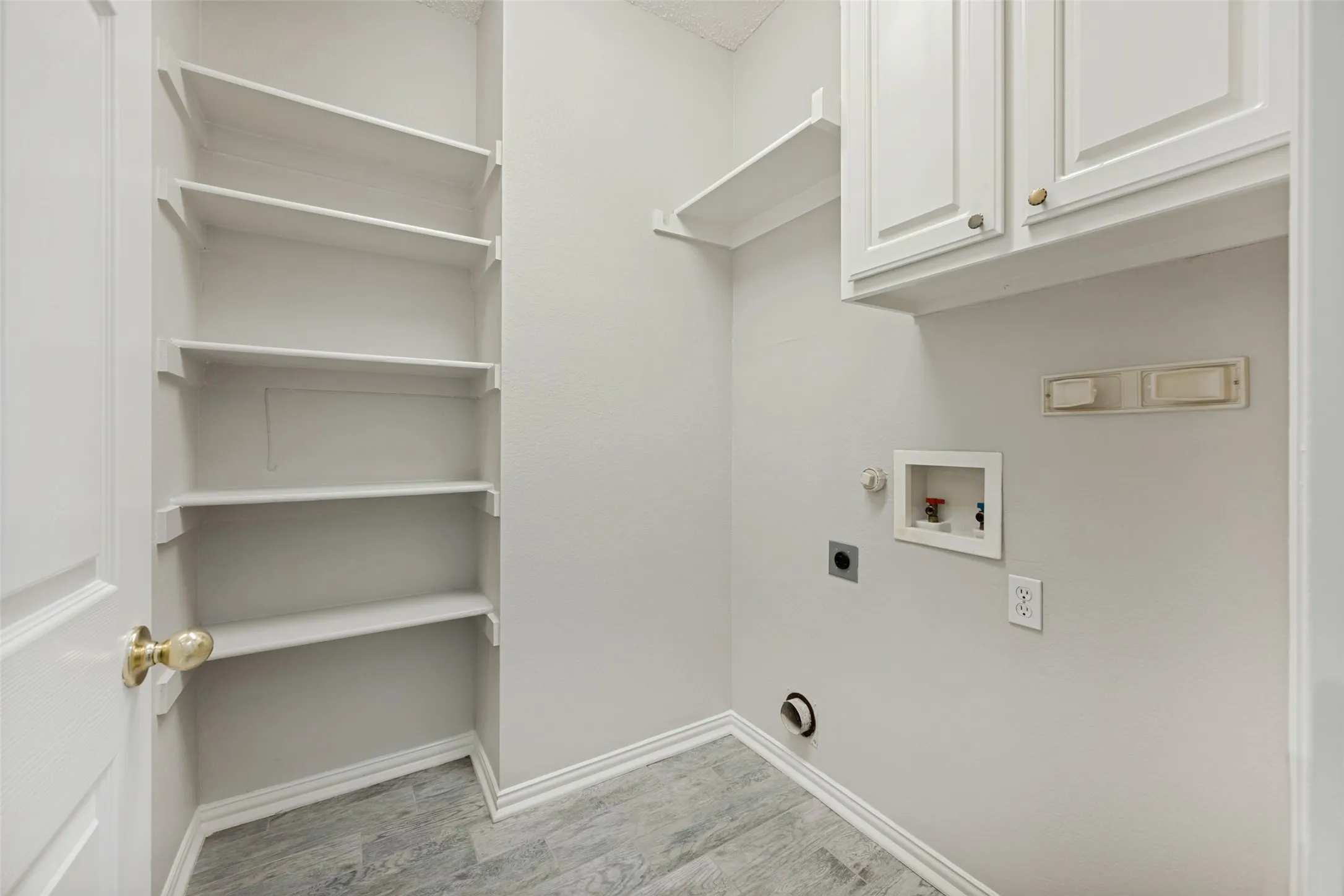 Dedicated utility area featuring wood-finish flooring and a neutral color palette