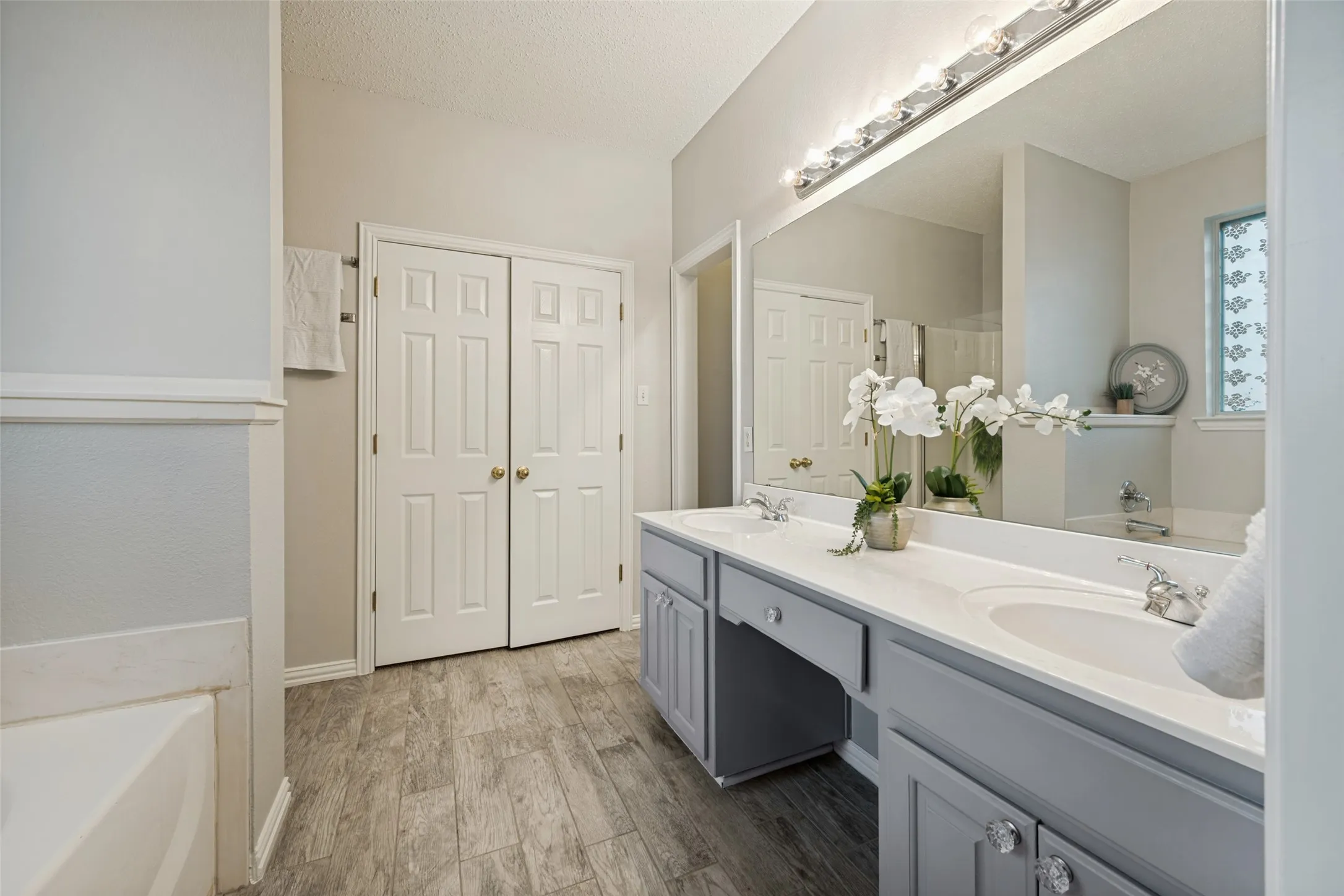 Bathroom featuring a double vanity with light gray cabinetry, white countertops, and dual integrated sinks