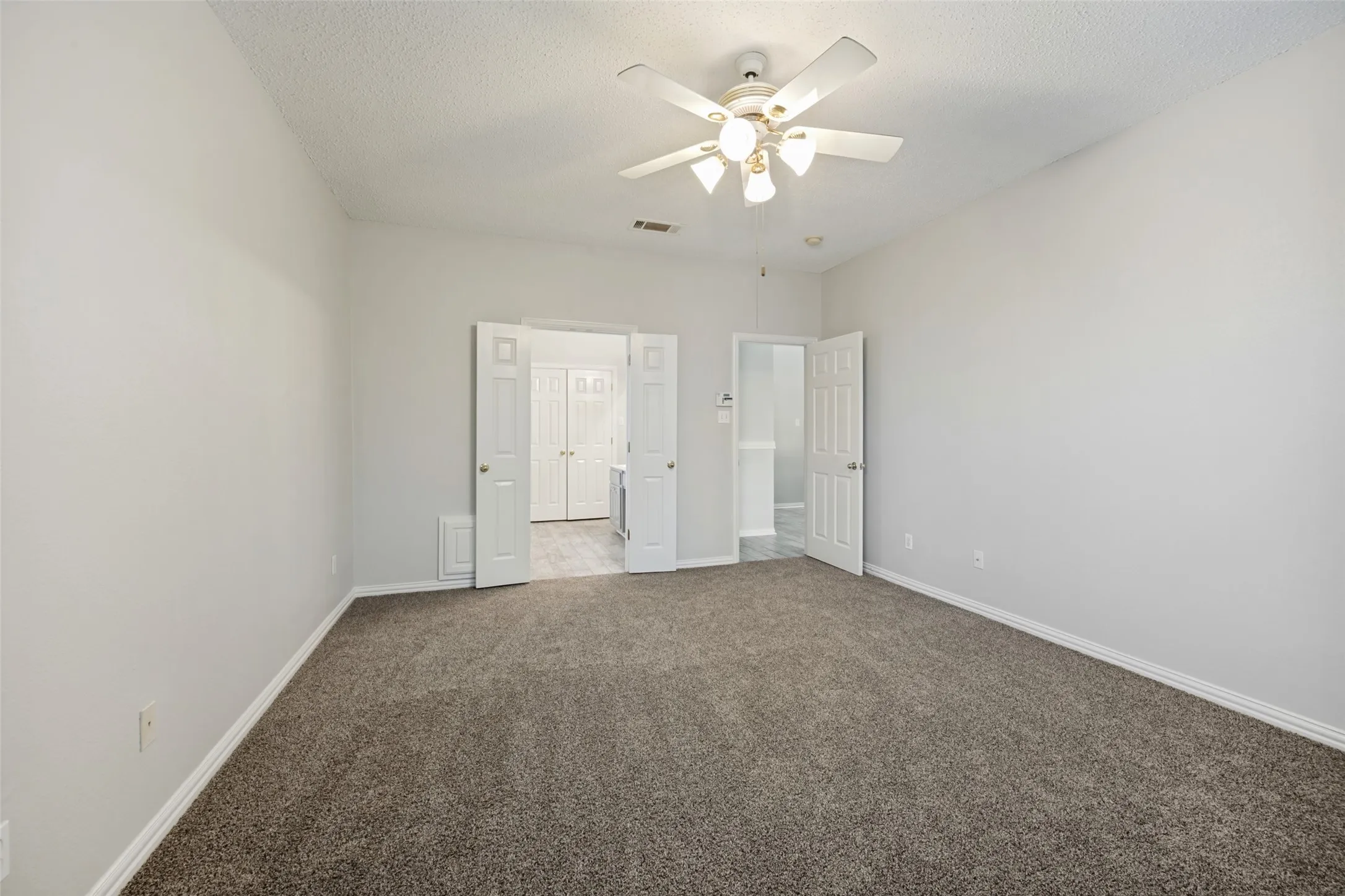 Spacious room with neutral wall tones and textured carpeting