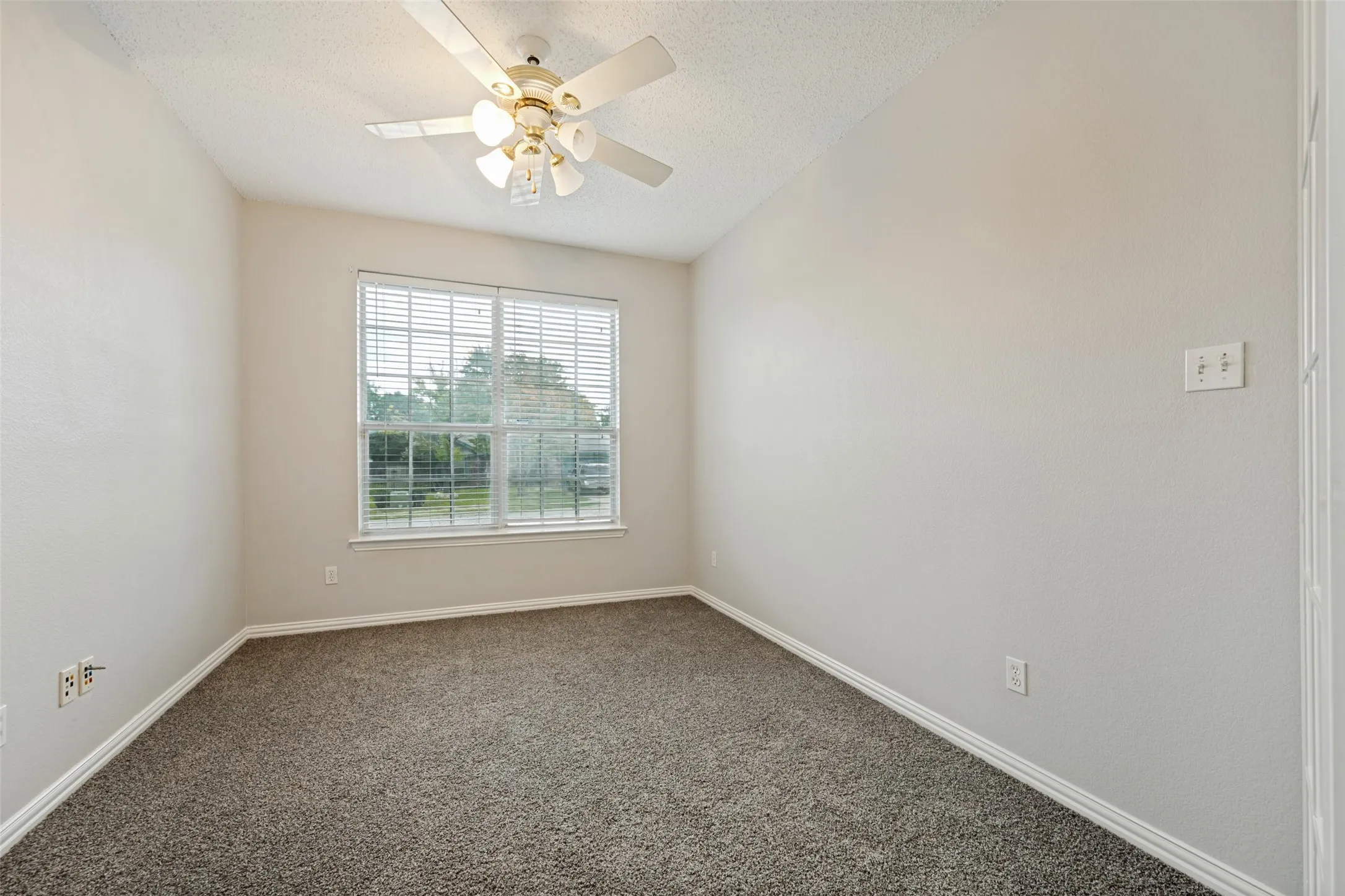 Carpeted room featuring a ceiling fan with integrated lighting, a window with horizontal blinds, and neutral wall tones