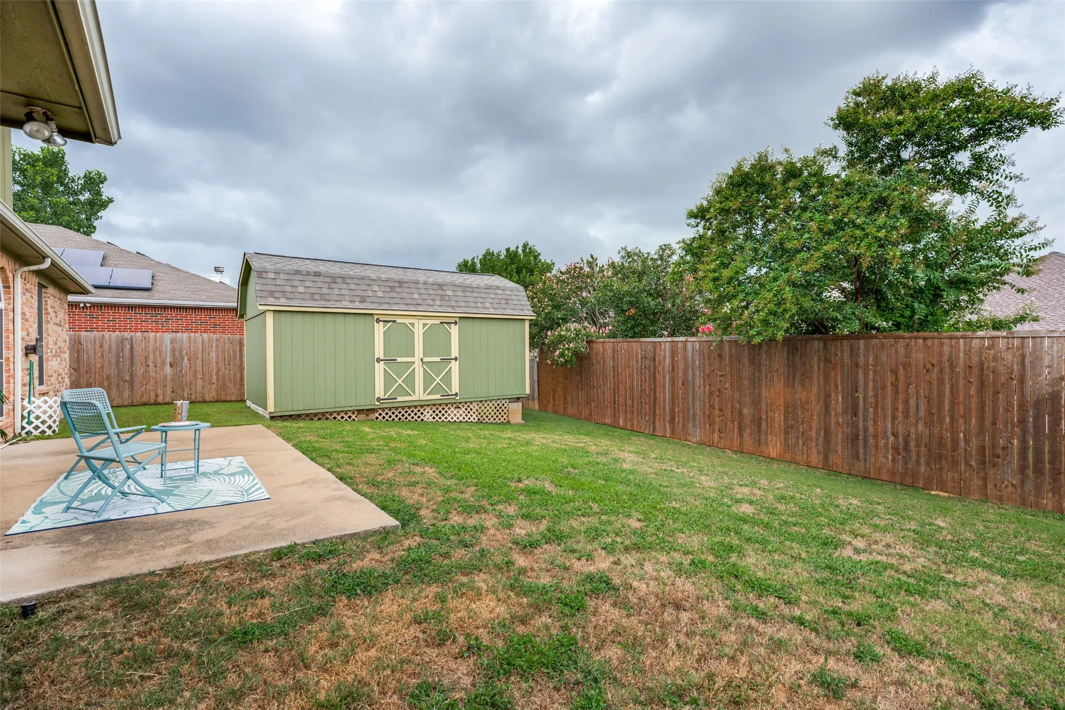 Expansive concrete patio with a detached storage shed featuring a gambrel roof and double doors
