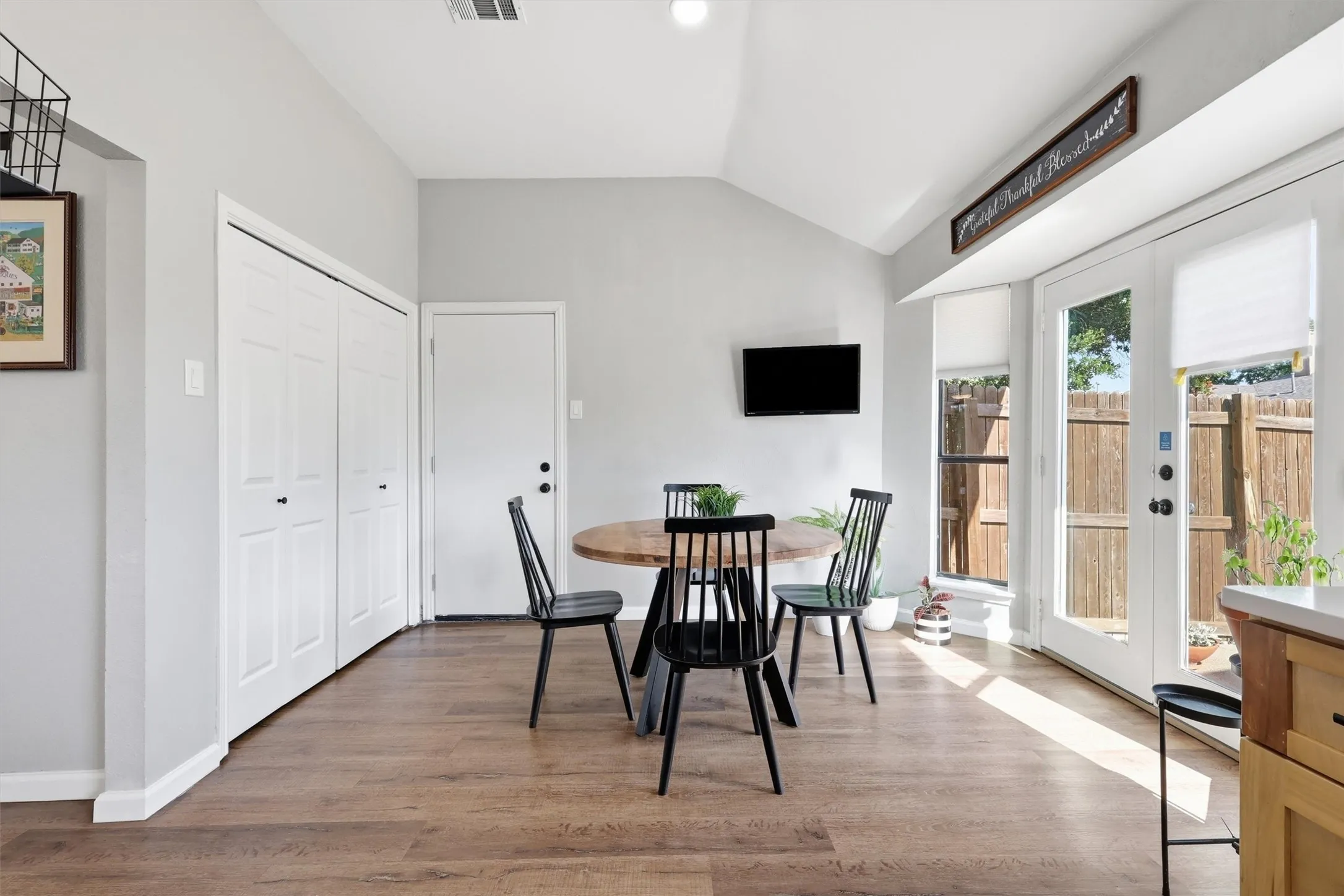 Dining area featuring wood-finish flooring, vaulted ceiling, and white baseboards