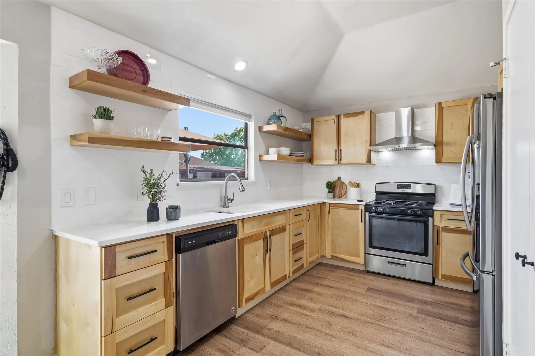 Kitchen featuring wood-finish flooring, white countertops, natural wood cabinetry, stainless steel appliances, and open shelving